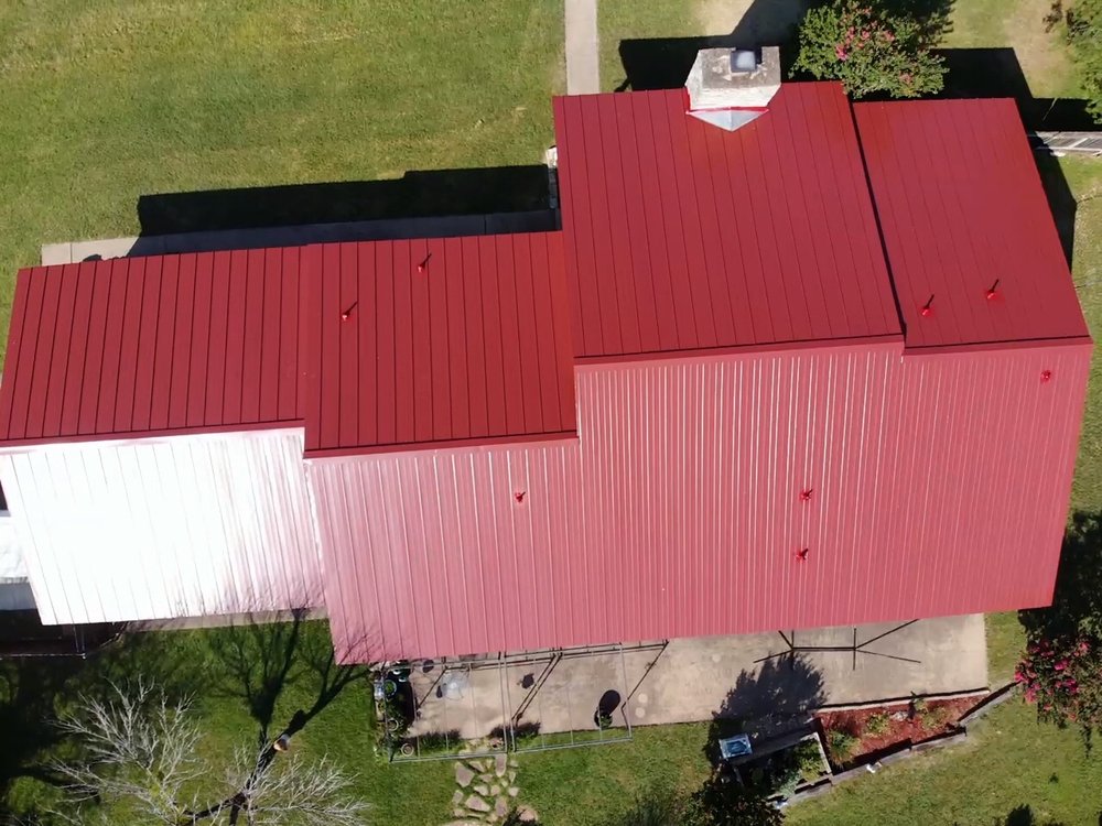 Bright barn red standing seam gable roof with a chimney and cricket, offering a vibrant and functional design.