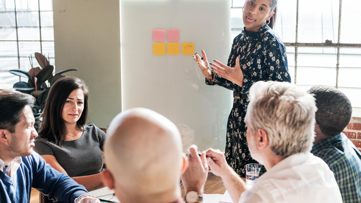 A workshop facilitator presenting a front of a group of colleagues  