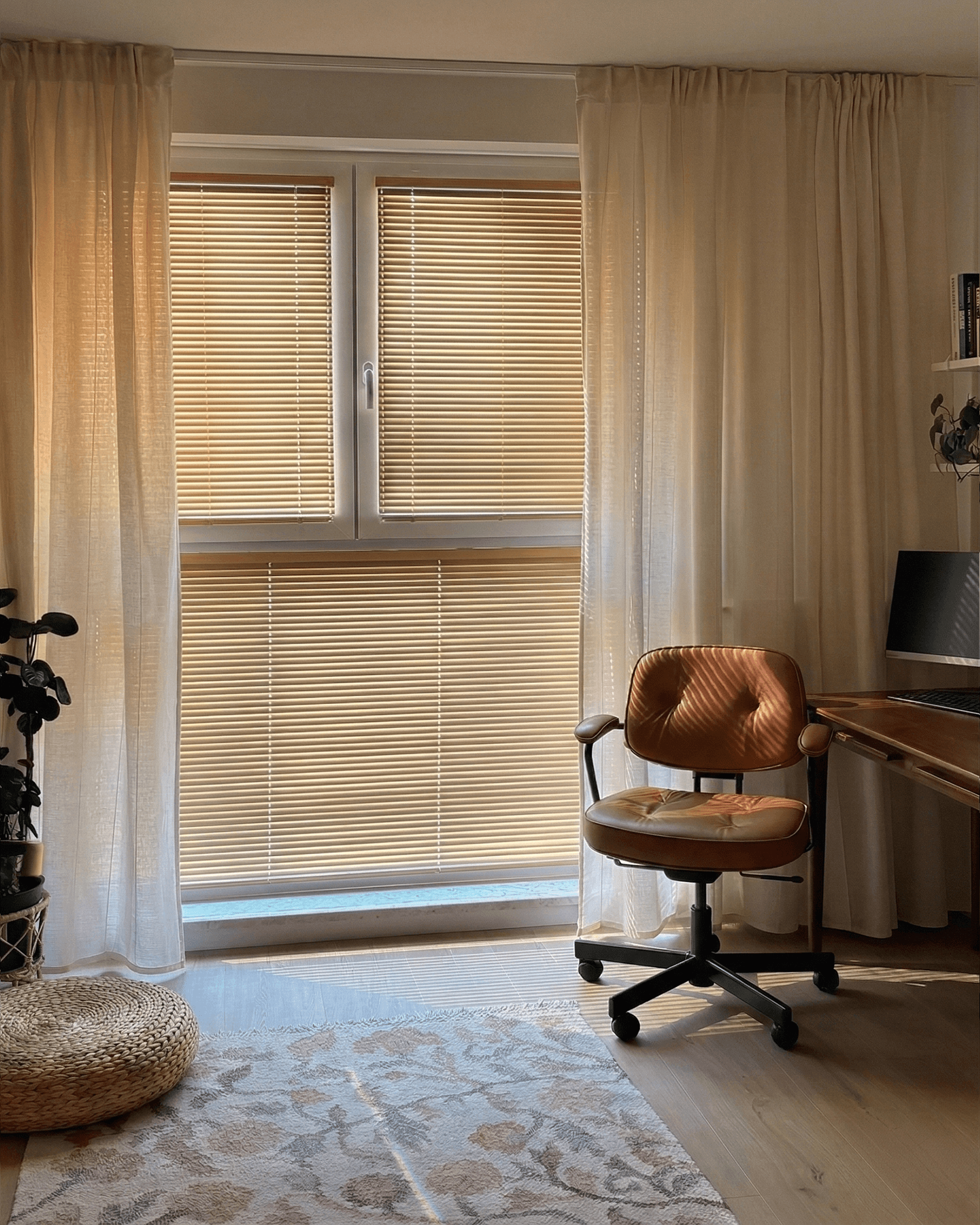 Jasne żaluzje drewniane w duecie z lekkimi zasłonami w domowym biurze. Nowoczesne osłony okienne na wymiar od HeyShade Pruszków – idealne do pracy przy biurku.