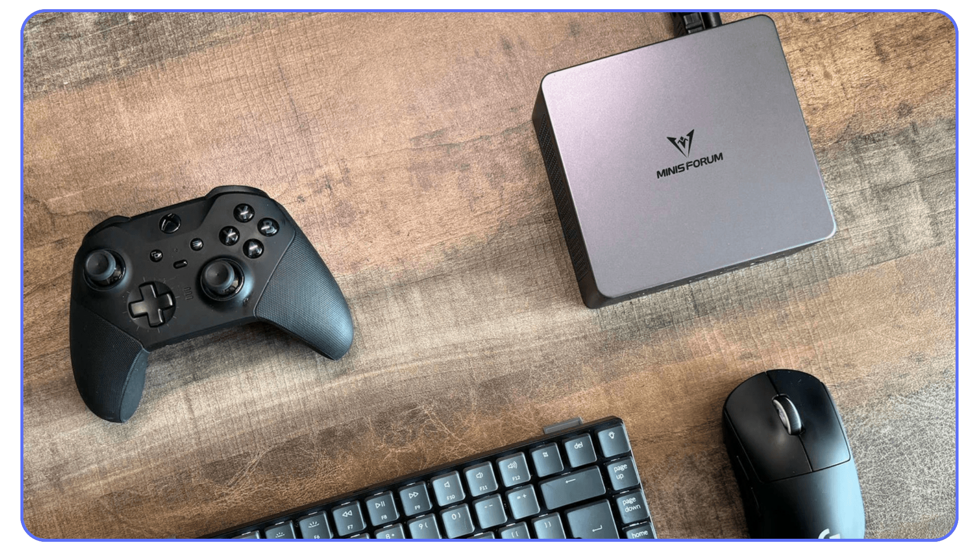 A Minisforum compact desktop PC alongside a game controller, keyboard, and mouse on a wooden desk.