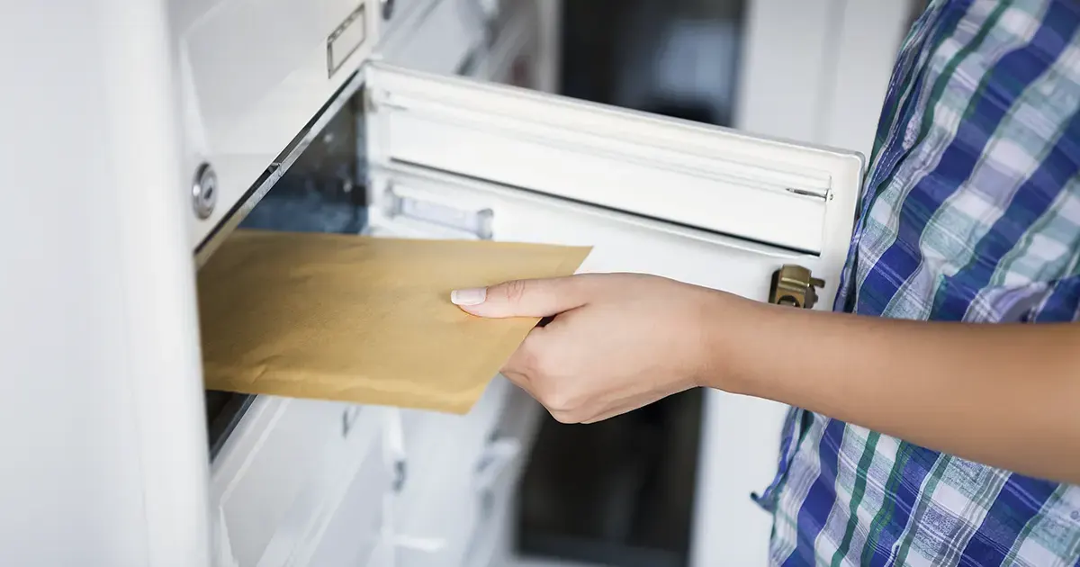 Woman retrieves letter from the mailbox.