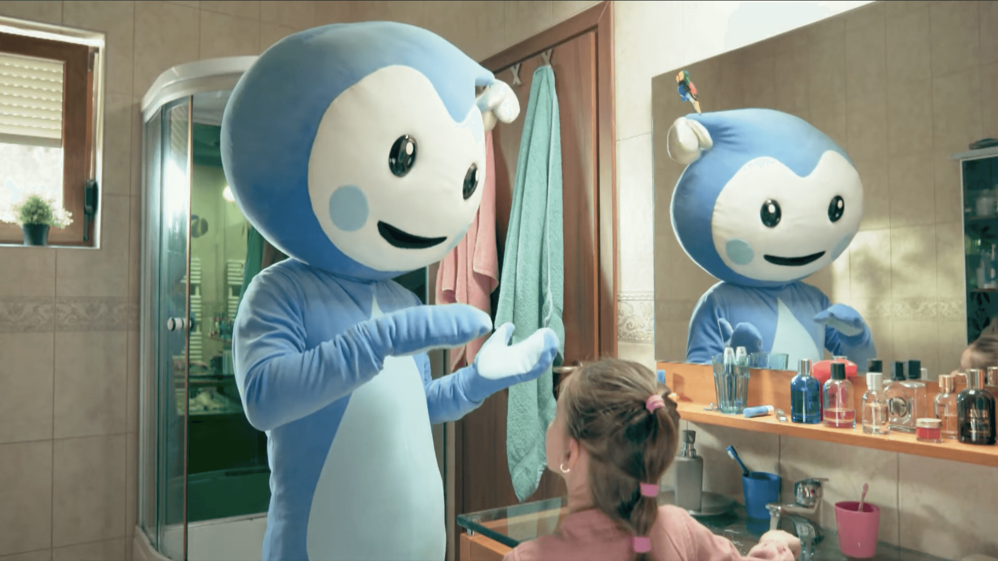 Cseppbarát kék kabalafigurája a fürdőben az égési sérülés kezelésést tanítja a kislánynak.