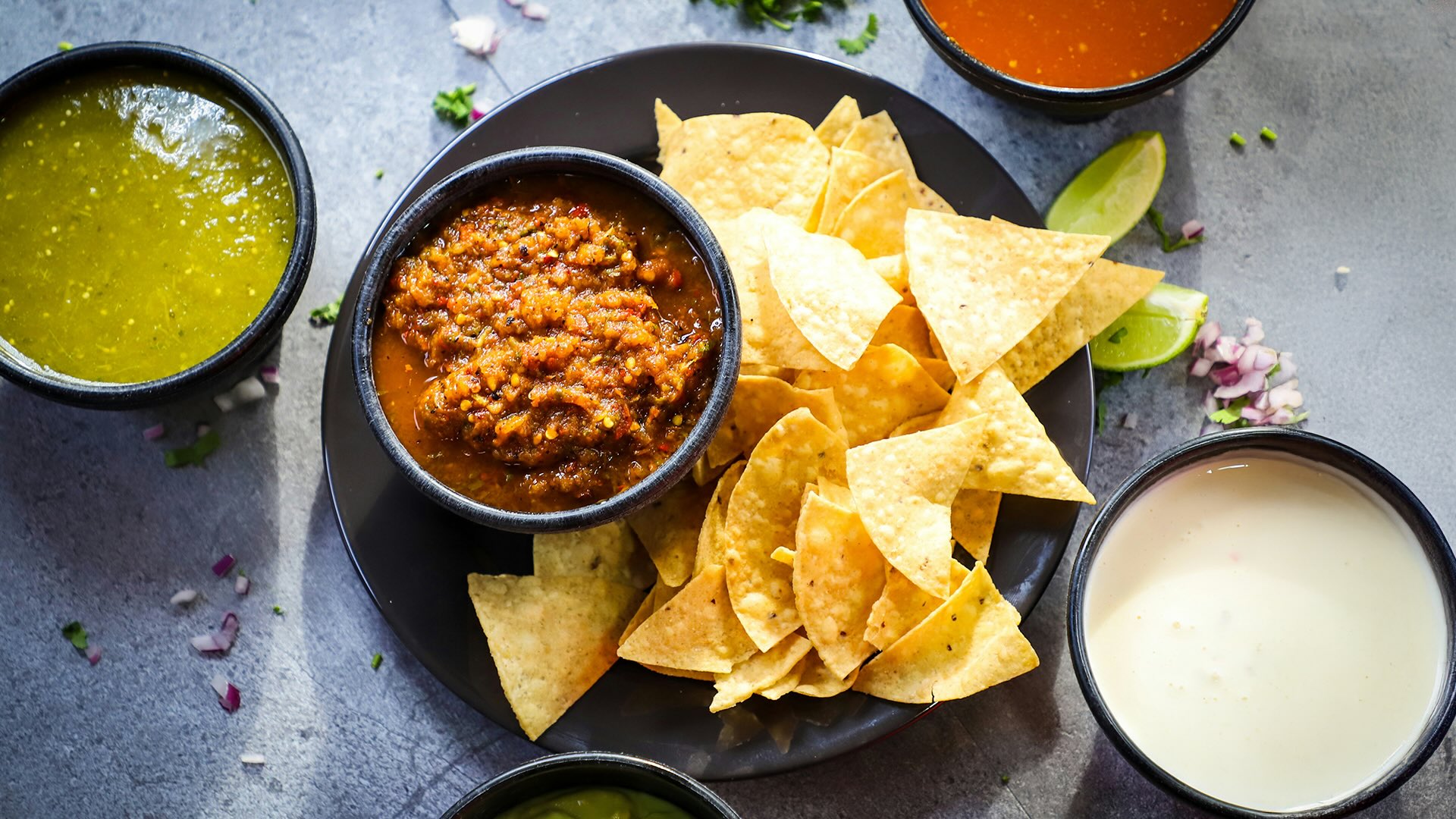 table top with chips, salsa and sauces