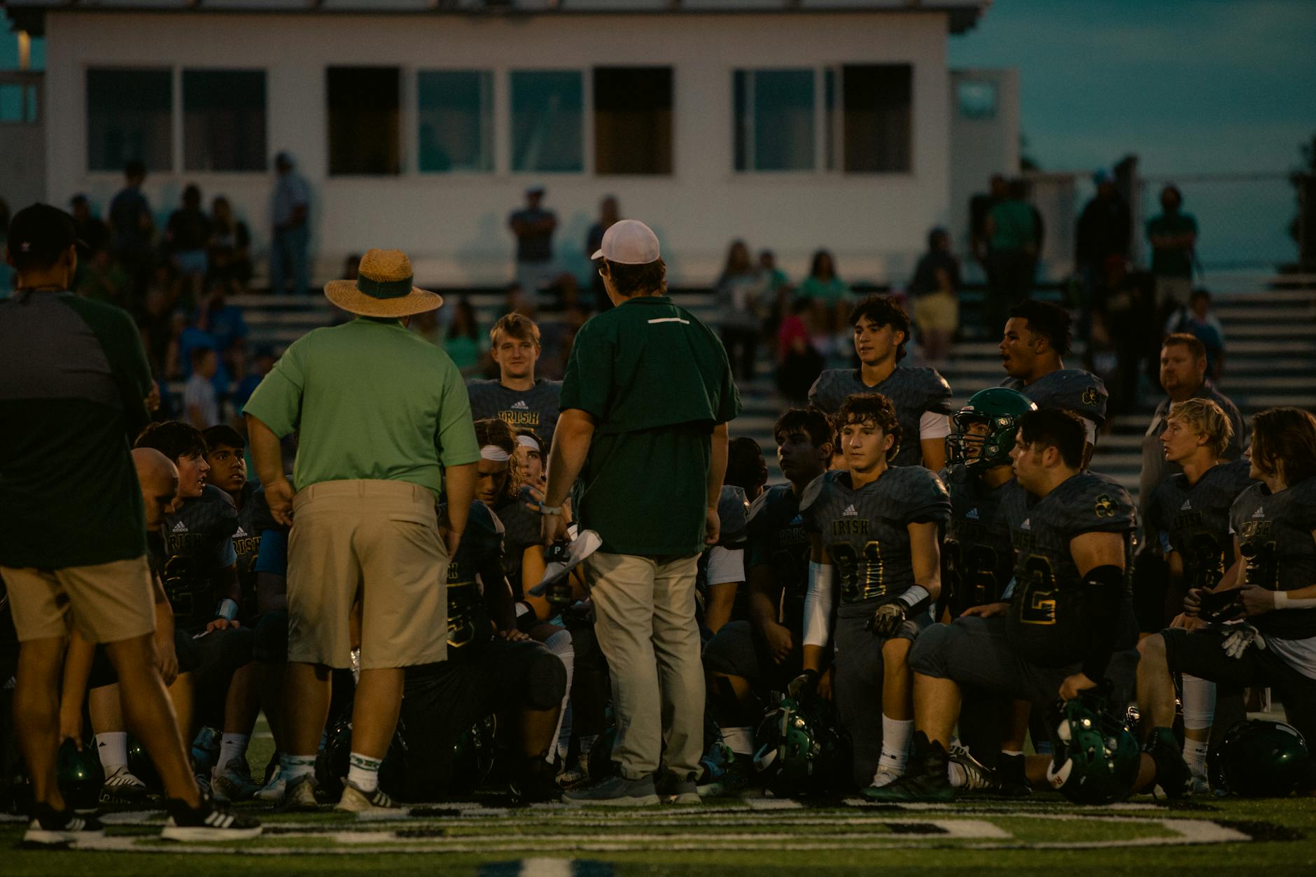 College football coach instructing players during summer camp with clipboard