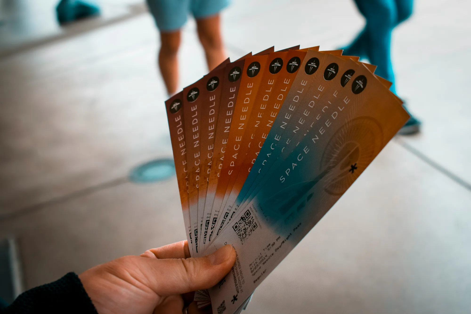 A person's hand holding several tickets to the Space Needle. 