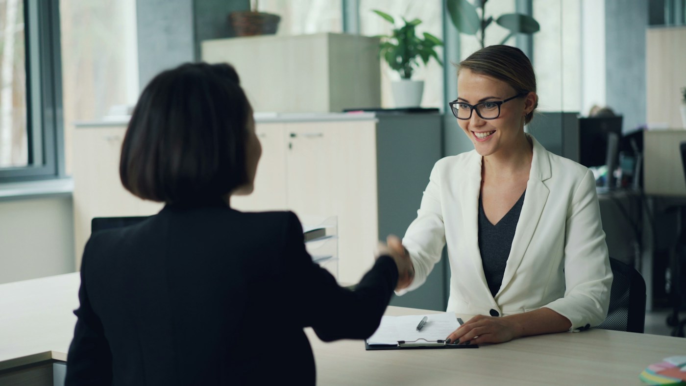 two people shaking hands across an office desk