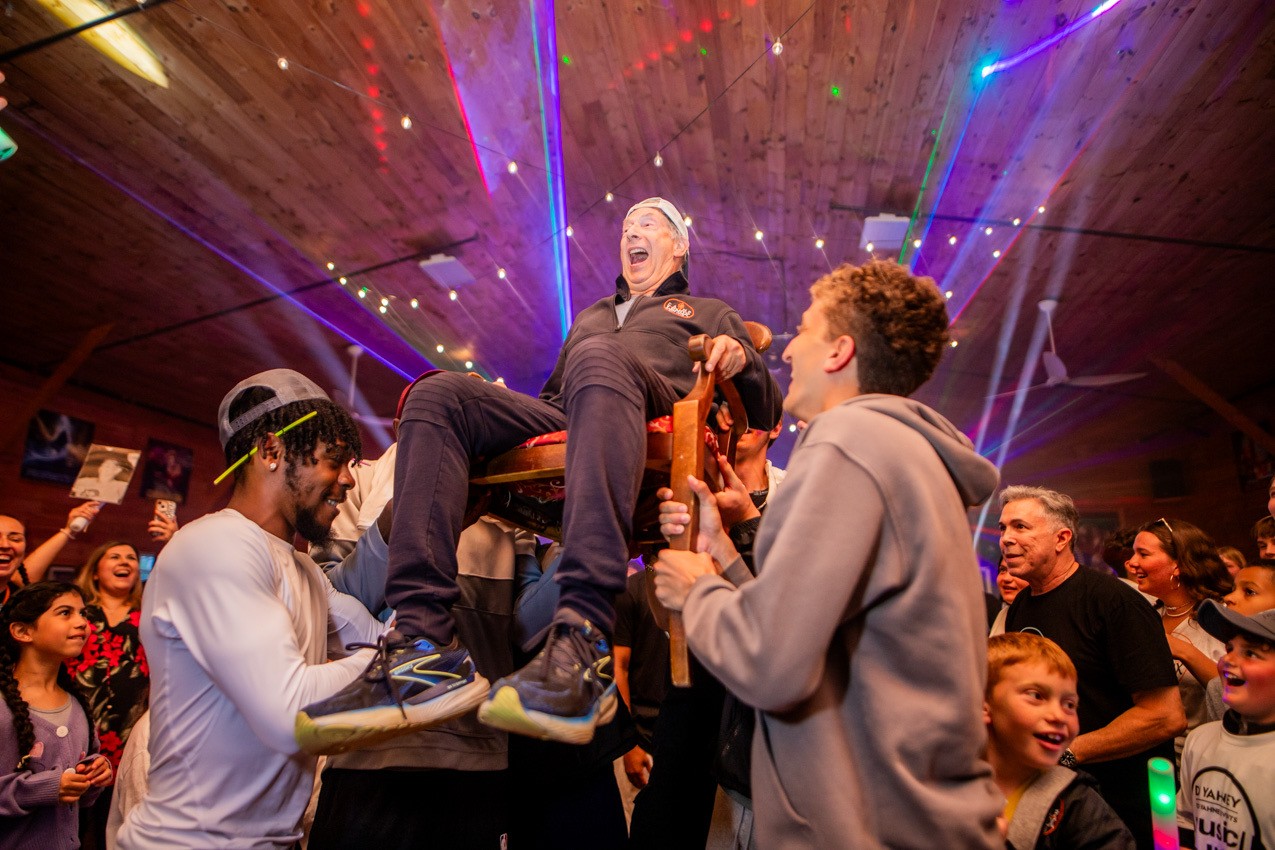 Rich Moss lifted in a chair by campers during a camp celebration