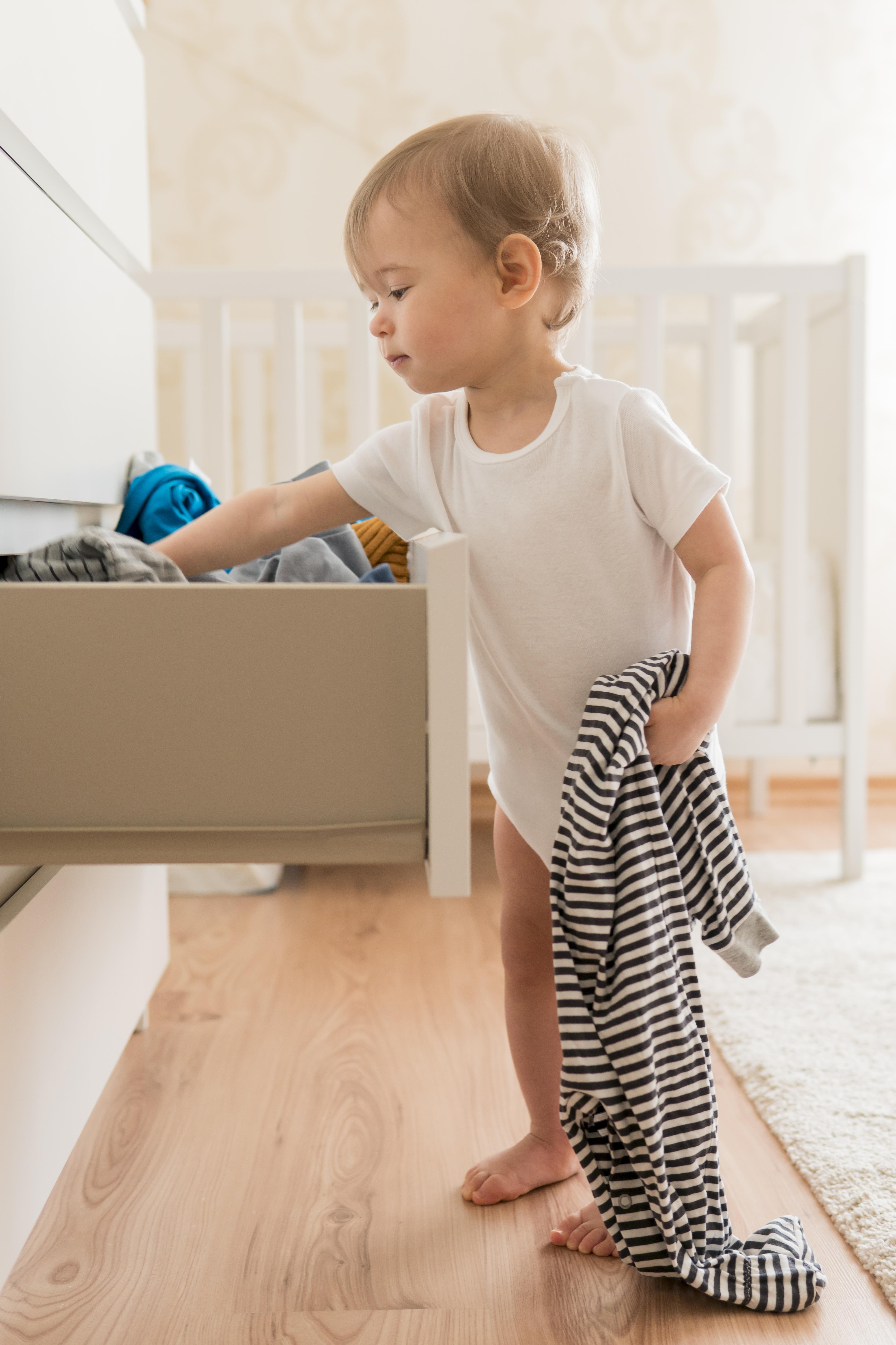 Baby pulling clothes from a low drawer on smooth, level timber flooring in a Brisbane home — no gaps or wobble, just safe everyday play