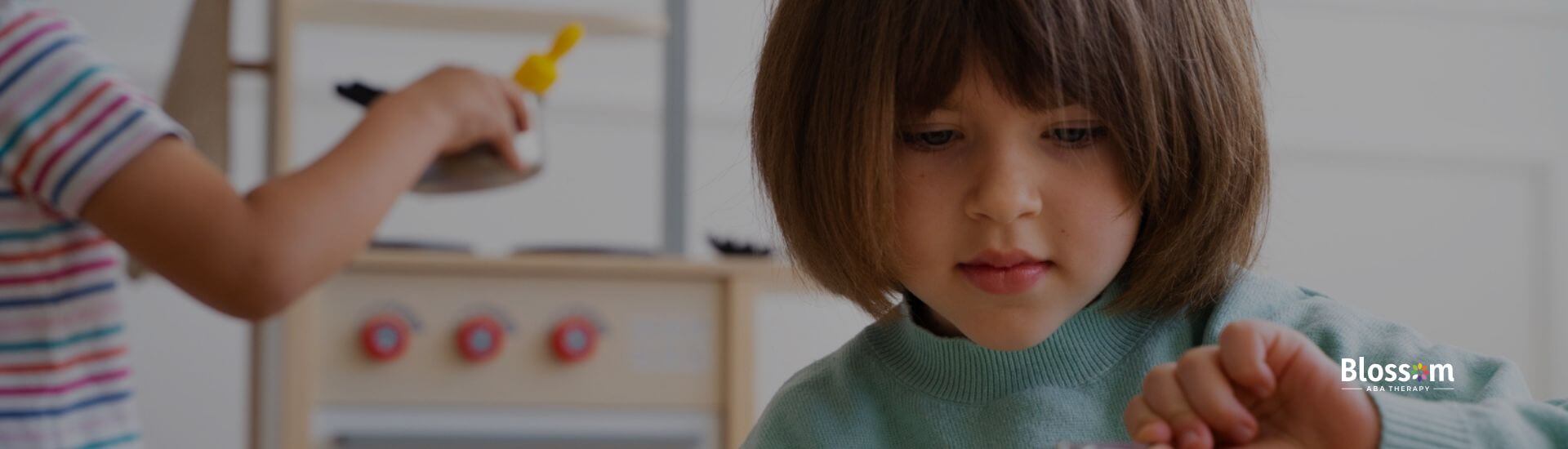 Child with autism focused on scooping pretend food while playing in a toy kitchen.