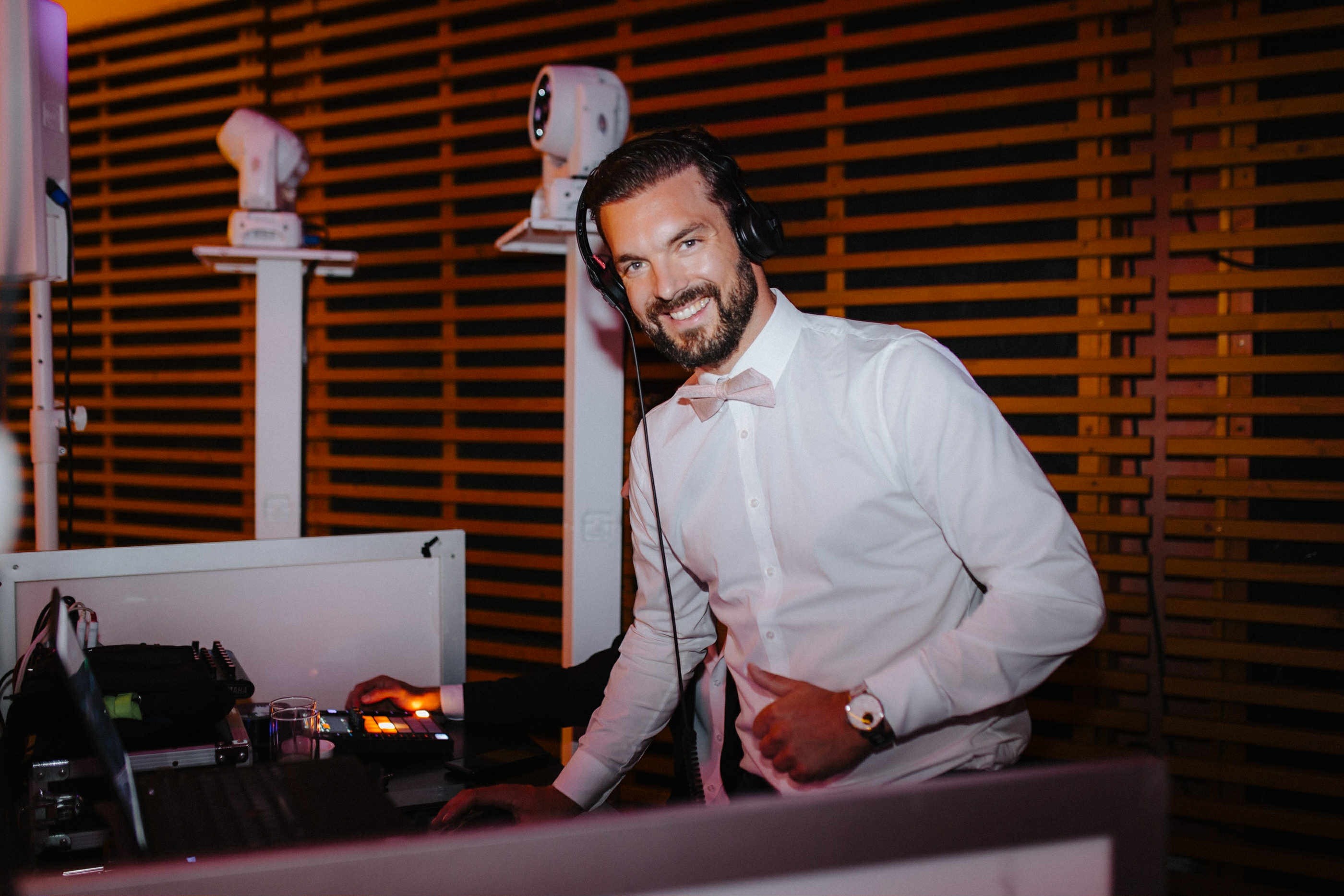 Fejhallgatós DJ mosolyog a fénytechnika mellett.