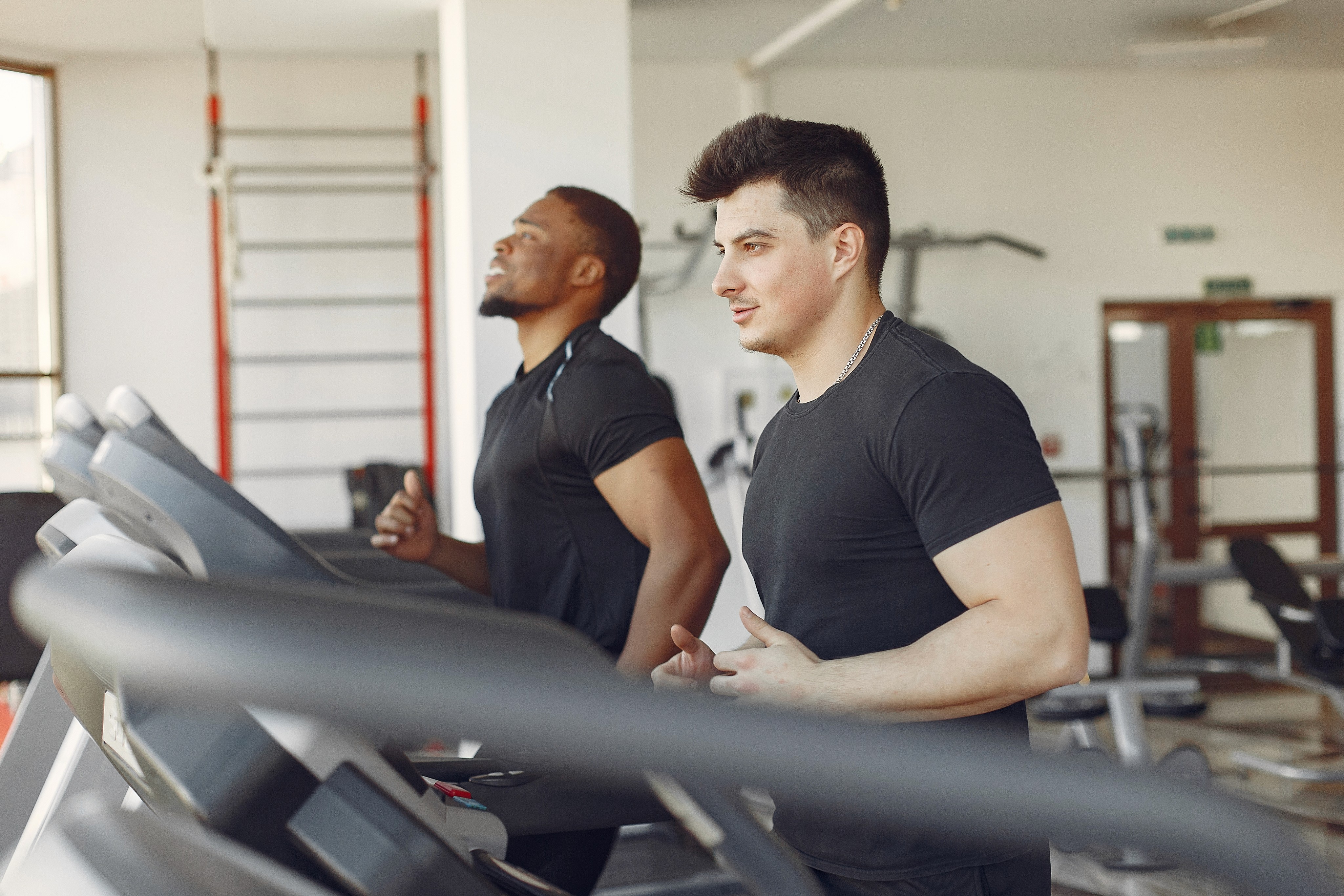 Two men running on treadmills in a gym.