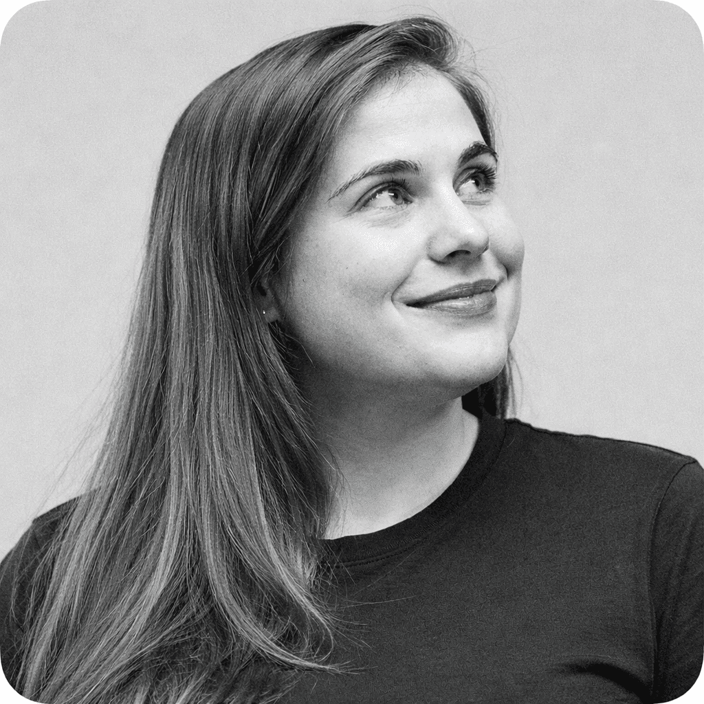 Portrait of a woman with straight long hair, in a dark t-shirt, set against a neutral backdrop.