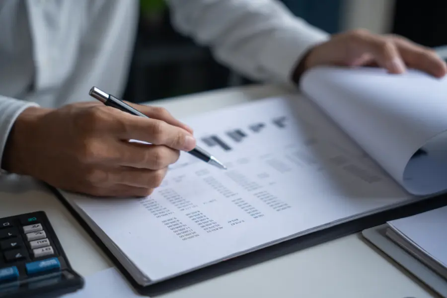AI receptionist streamlining administrative tasks as a professional reviews financial spreadsheets with a calculator on the desk.