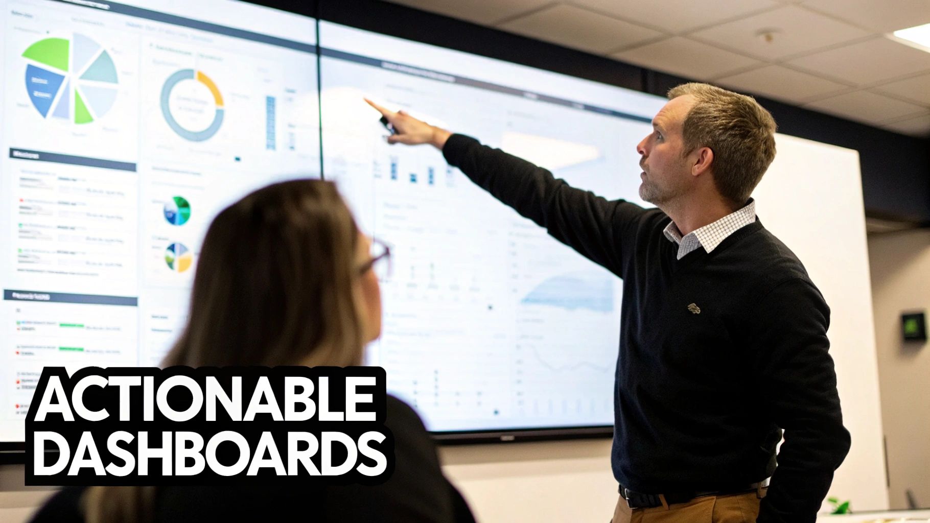A man points to a multi-screen data dashboard with various charts, explaining actionable insights to a colleague.