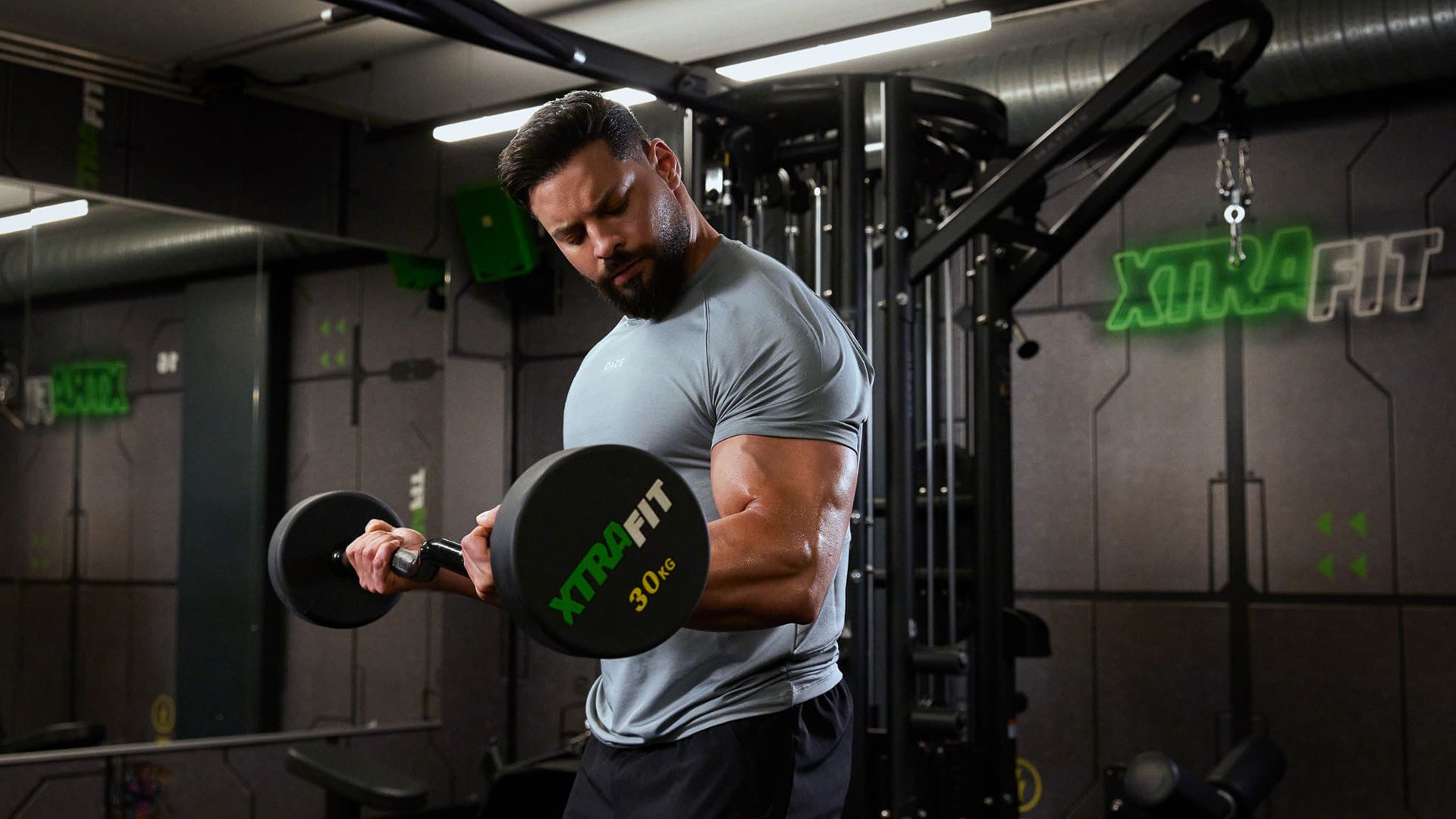 Sportlicher Mann trainiert Bizeps Curls mit SZ-Stange im XTRAFIT Fitnessstudio