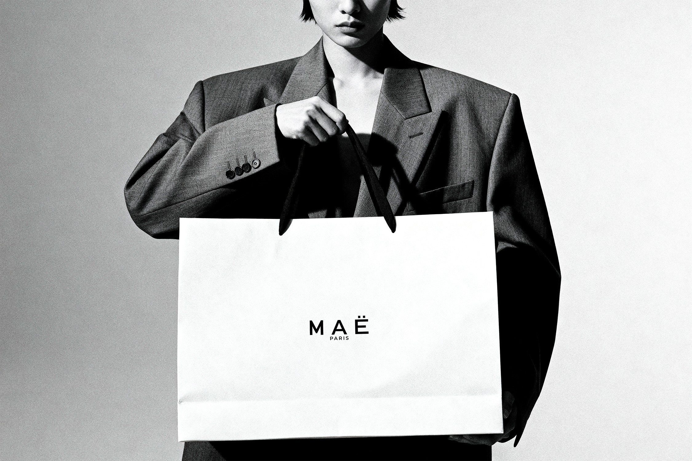 MAË PARIS luxury fashion shopping bag with minimalist branding held by a model in editorial style