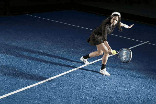 Player hitting a backhand on an indoor padel court