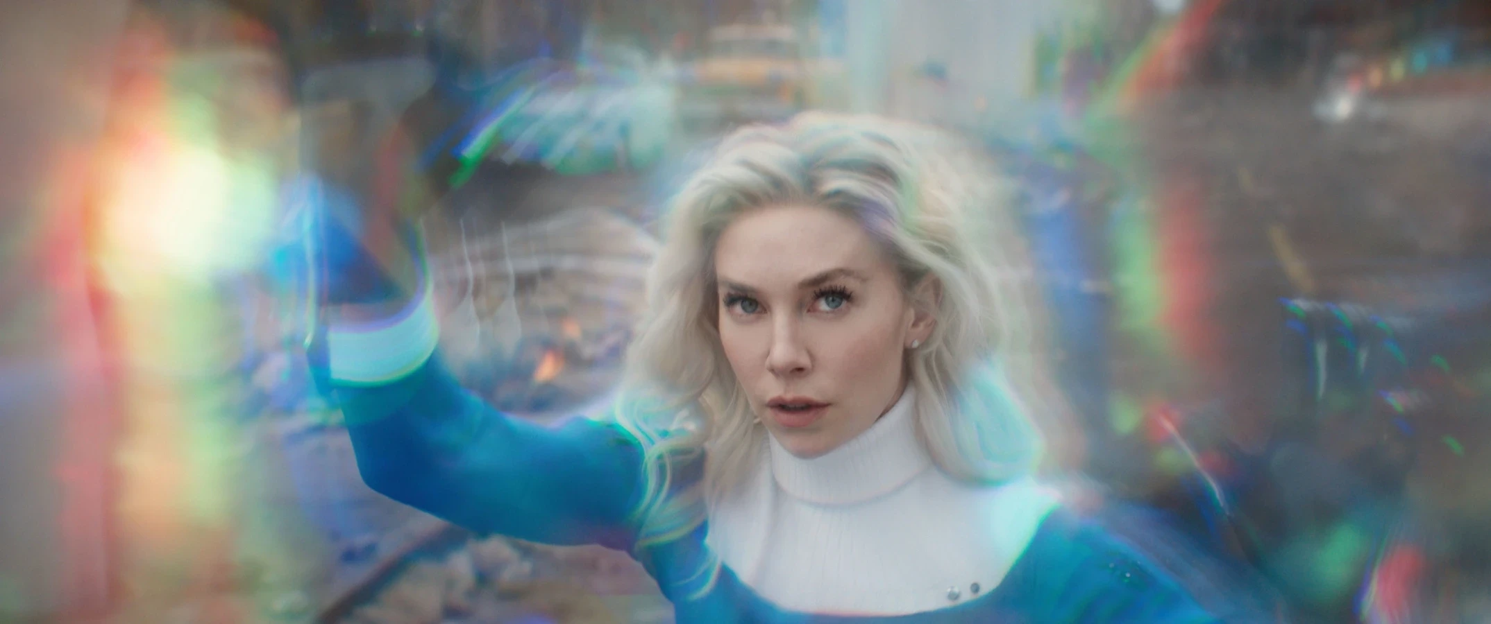 A woman with long white hair and a blue and white outfit appears to be casting a spell. Her hand is raised, and a swirling magical aura surrounds her. The background is blurred and colorful.