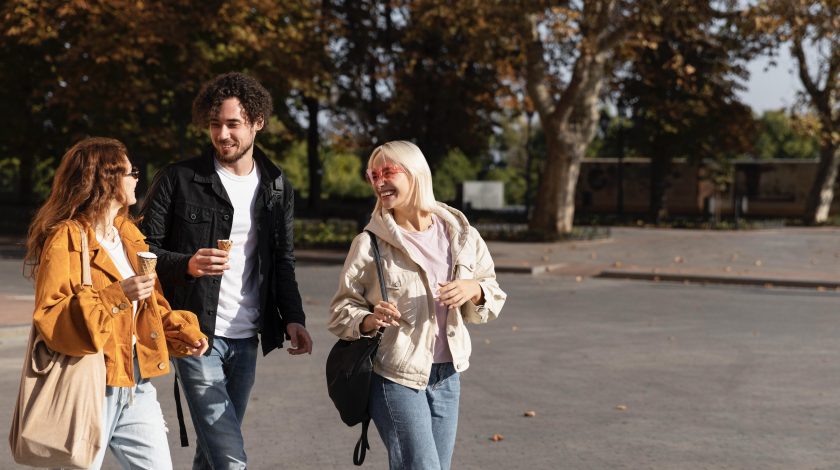 Three friends walking together on a sidewalk, enjoying their time outdoors in a sunny setting.