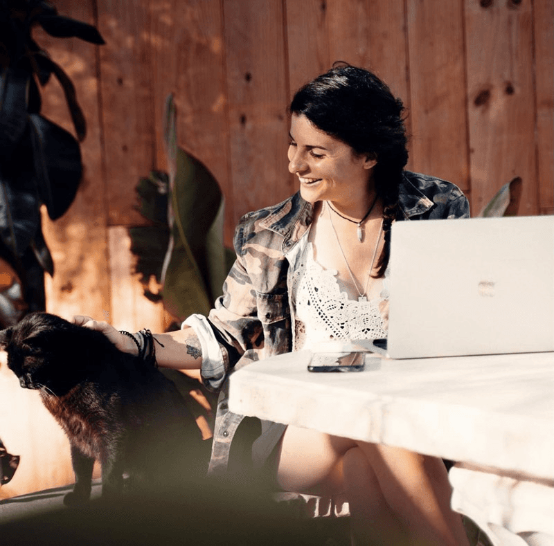 Woman petting black cat by laptop