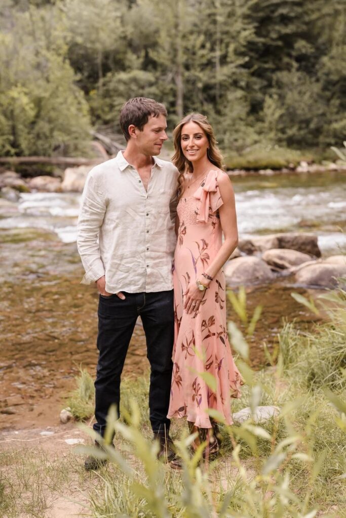 Couple standing by a river surrounded by trees in Aspen