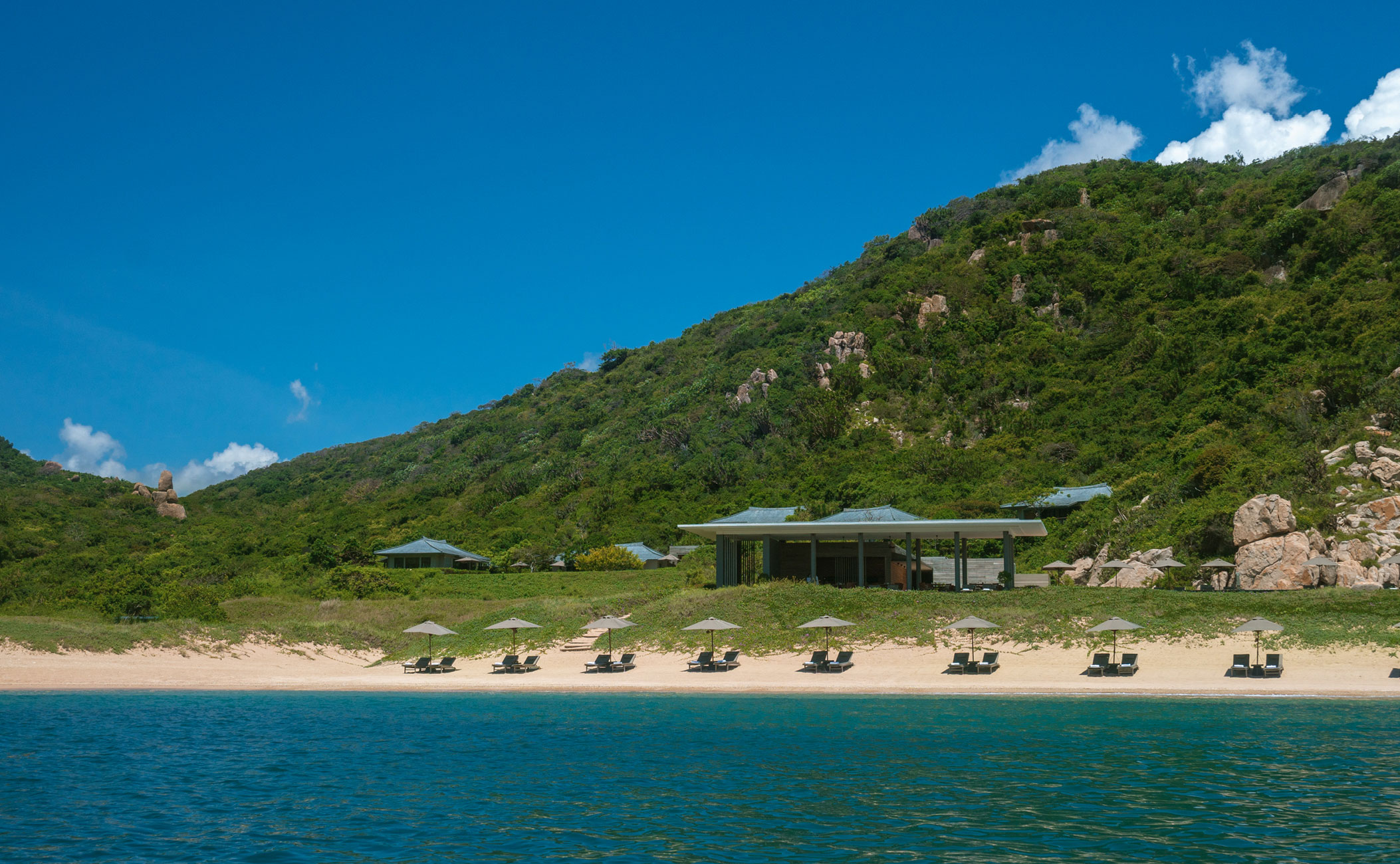 Amanoi's private beach with sun loungers along the shoreline and turquoise waters