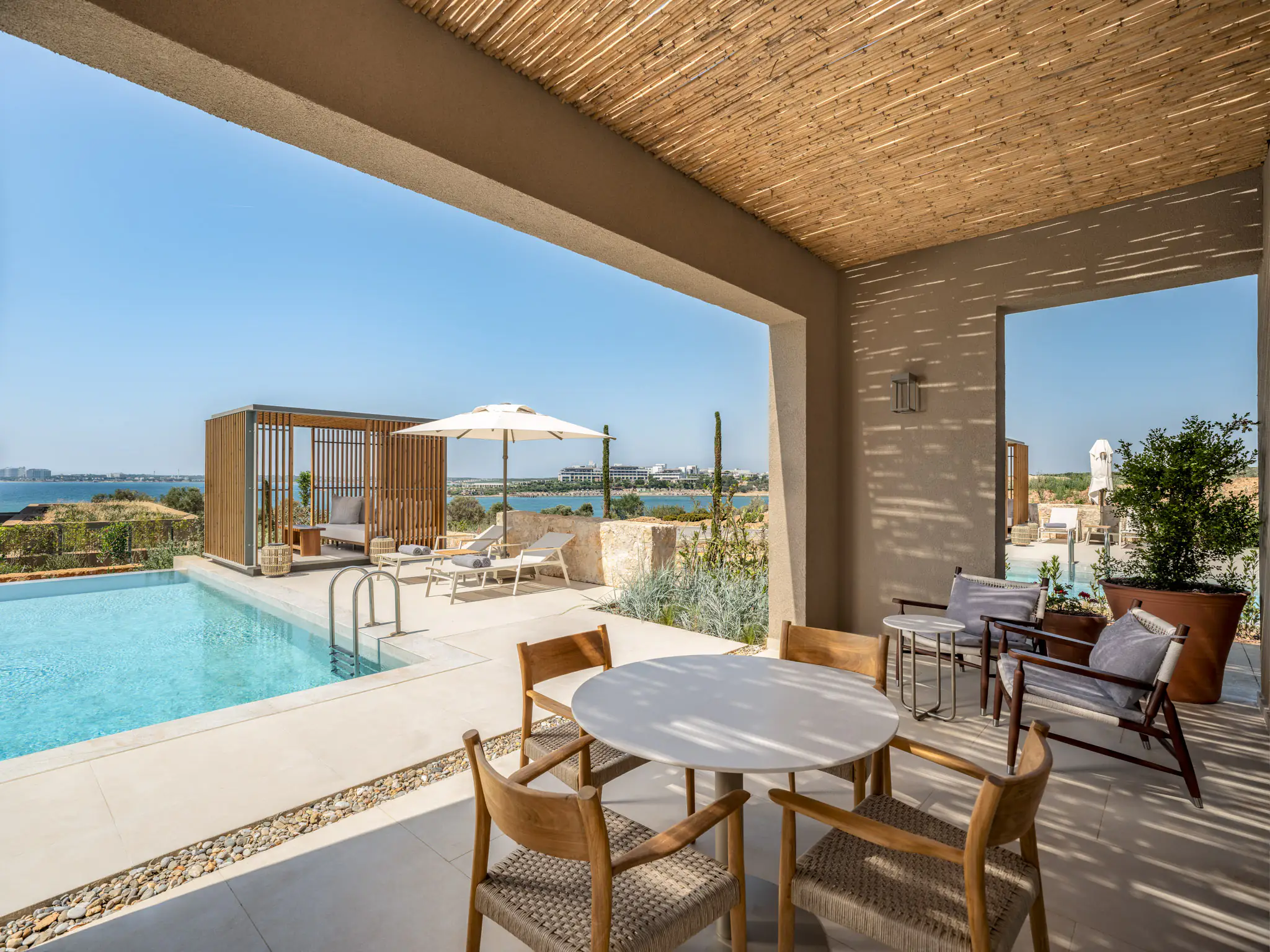 Dining table on the reed-ceilinged veranda beside the private pool and cabana