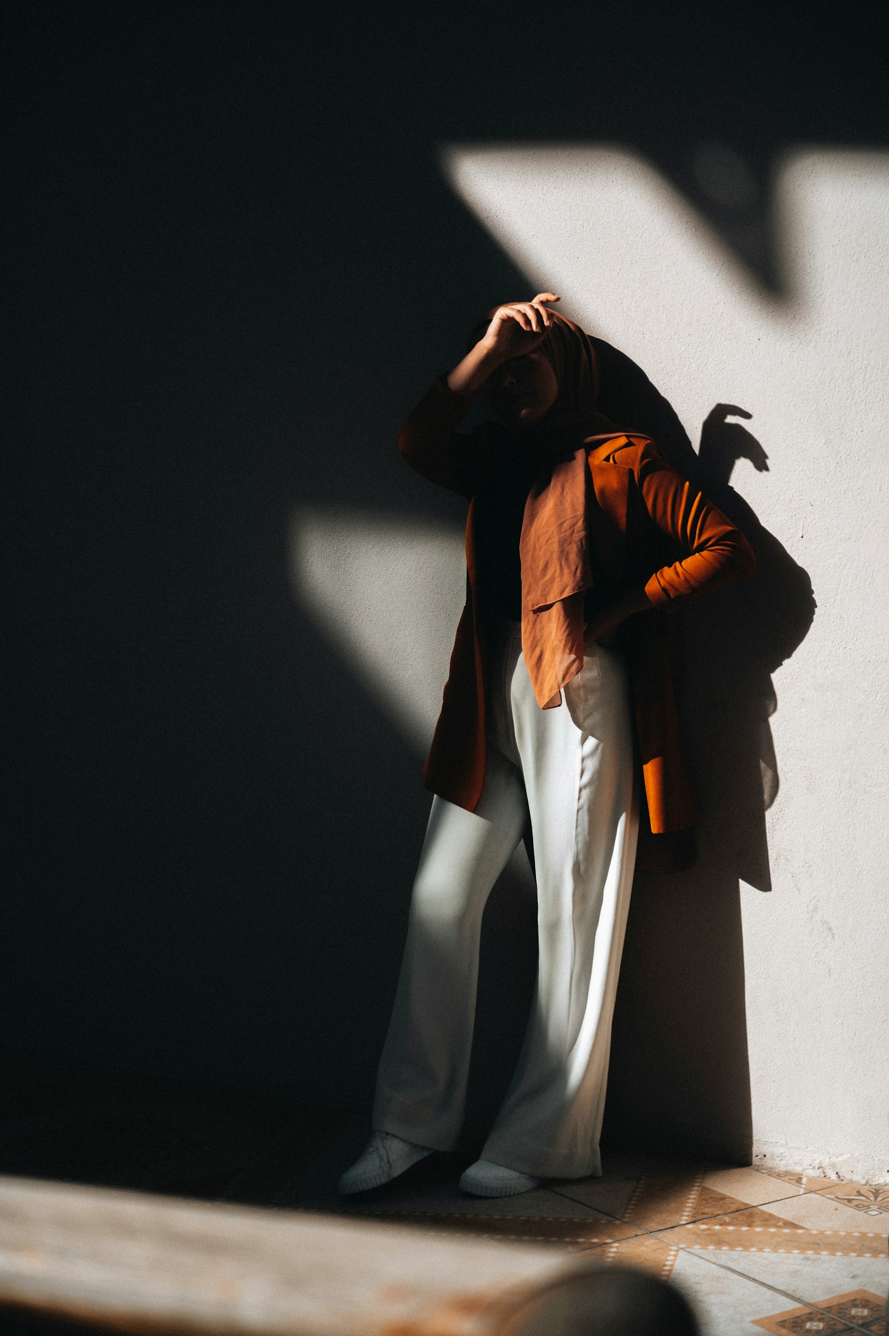 Hard light, a long shadow and a brown jacket on a white wall