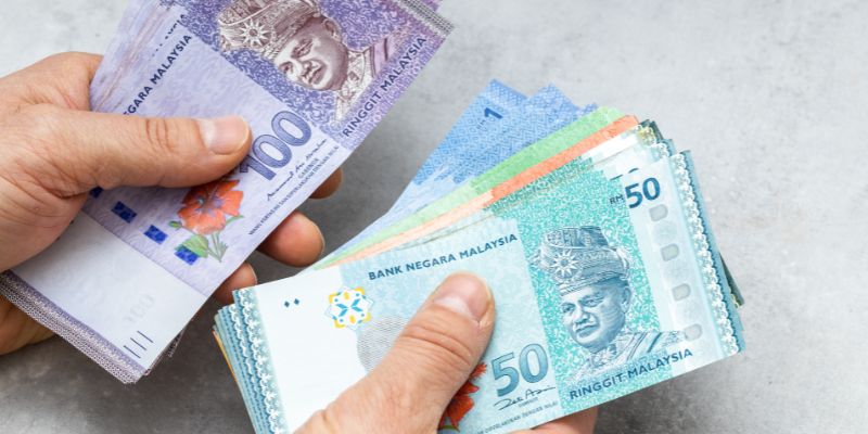 A person counting Malaysian ringgit