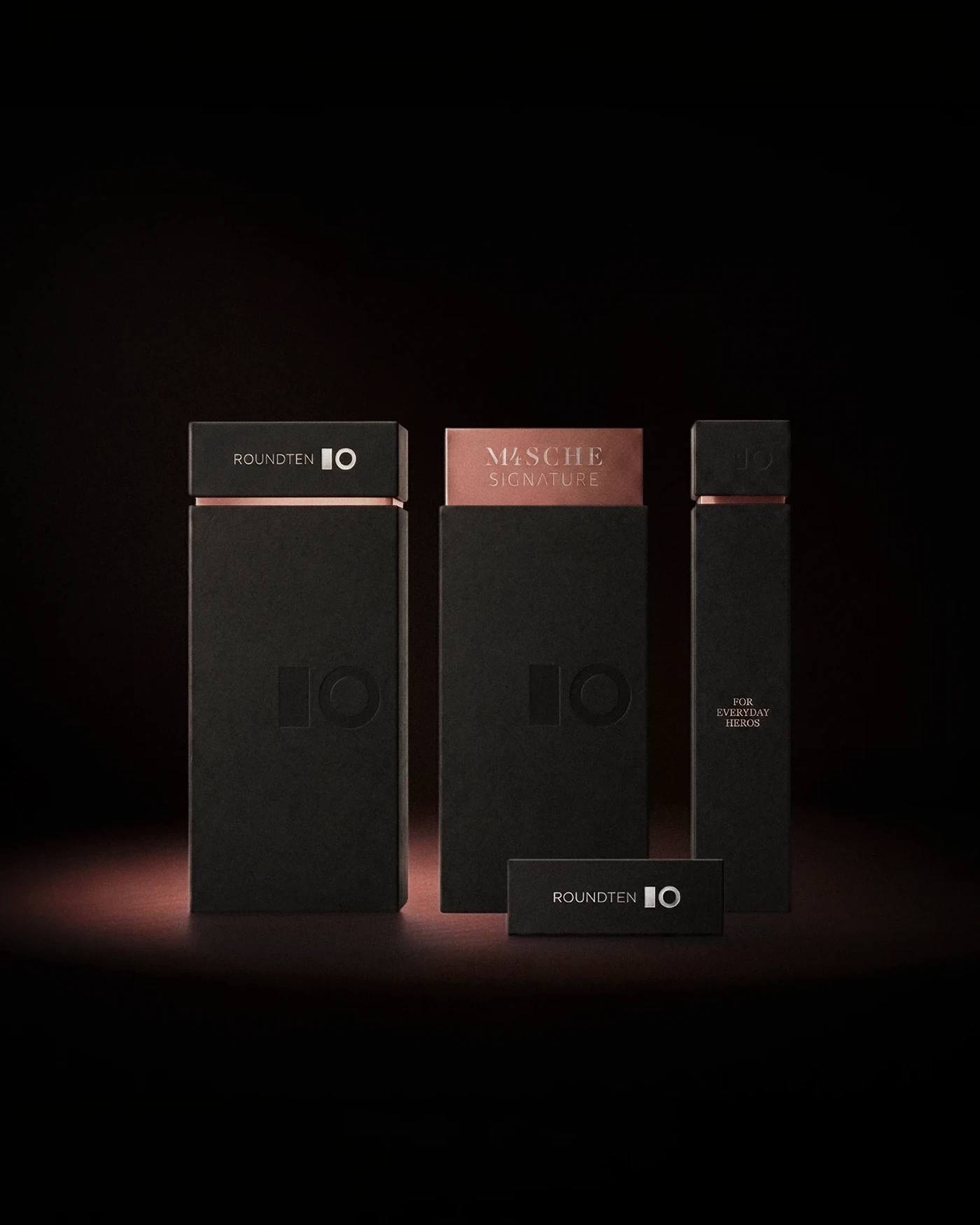 Roundten Mascherano Signature box with a bronze M4SCHE Signature lid between two black boxes, packaging design by Sebastian Saavedra