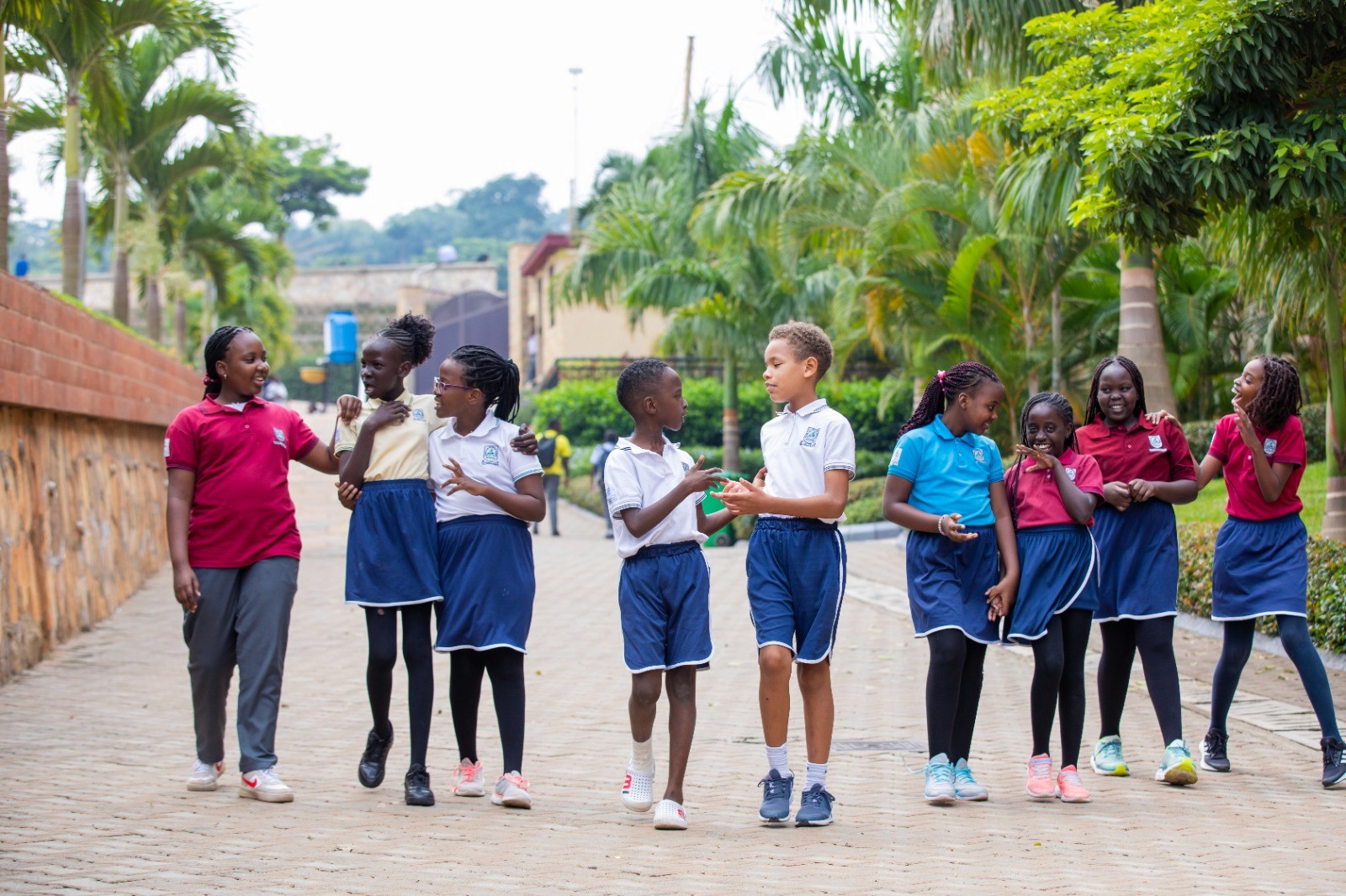 A student wearing a red uniform sits while holding a book in his hands