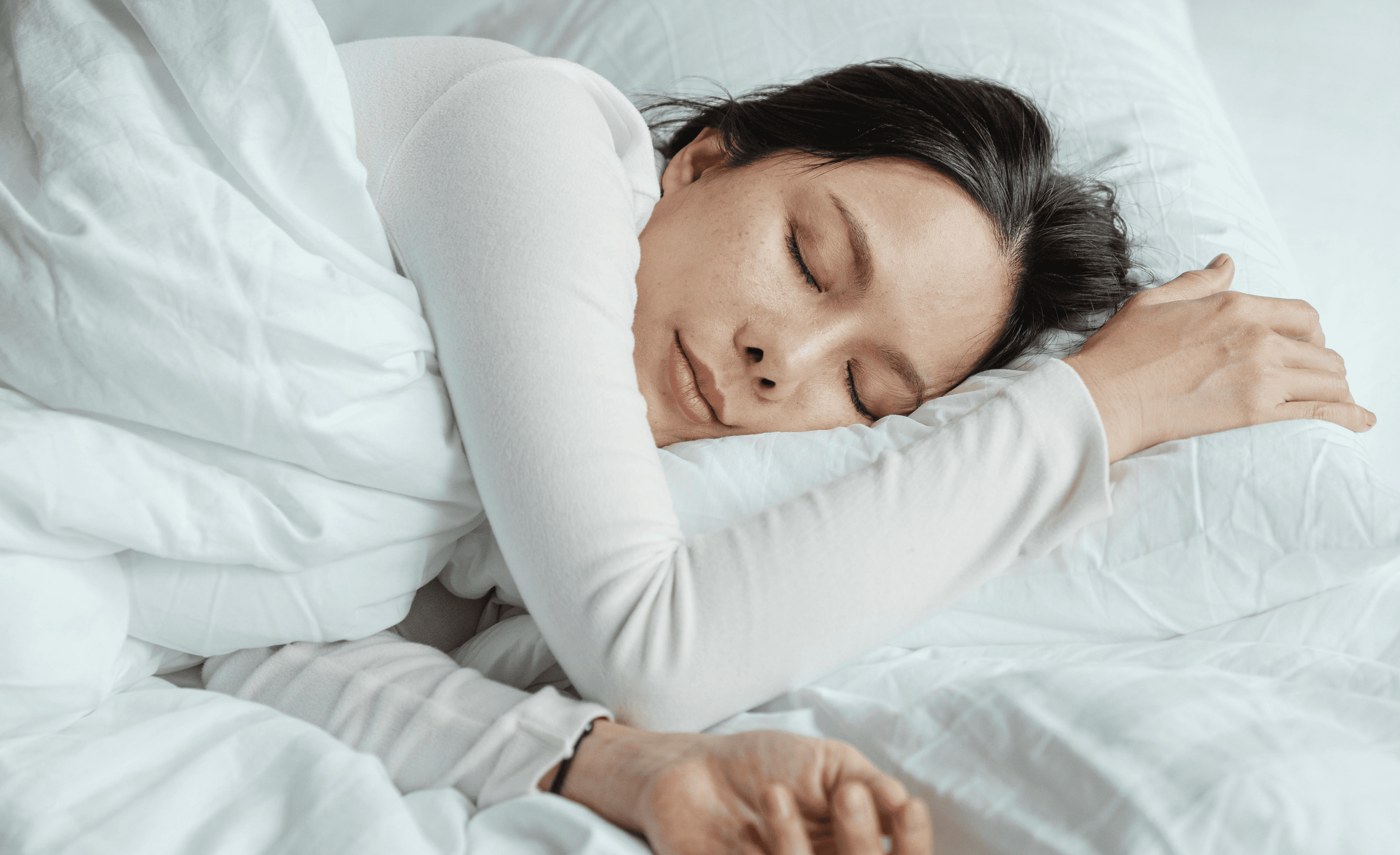 Woman sitting cross-legged on the edge of the bed in darkness