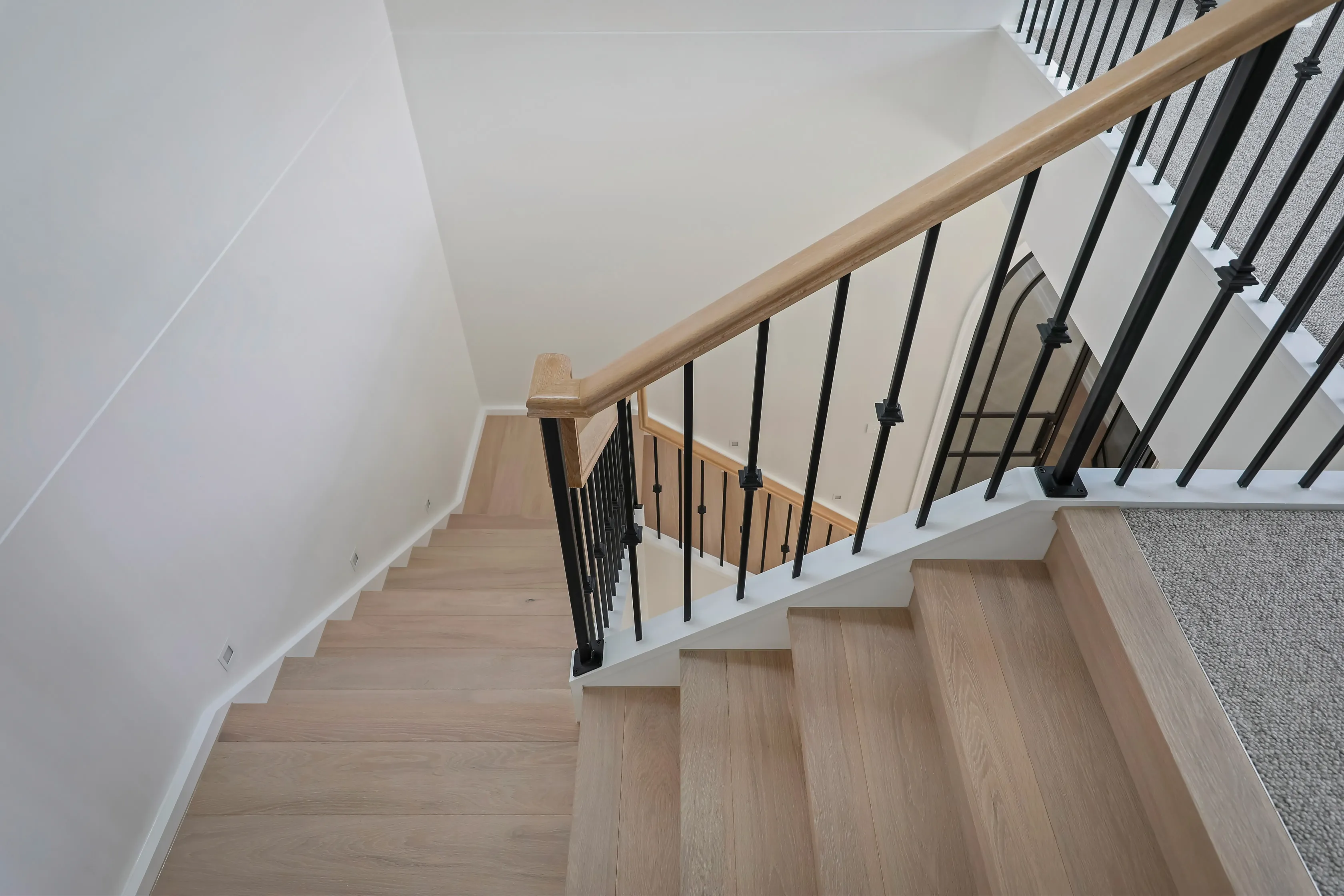 Looking down the Templestowe staircase with timber treads, an oak handrail and black wrought-iron balusters