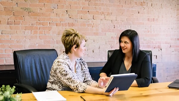 Two female executives in conversation at a desk