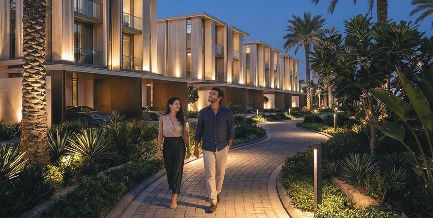 Couple walking along a lit path between Tilal Binghatti villas at dusk