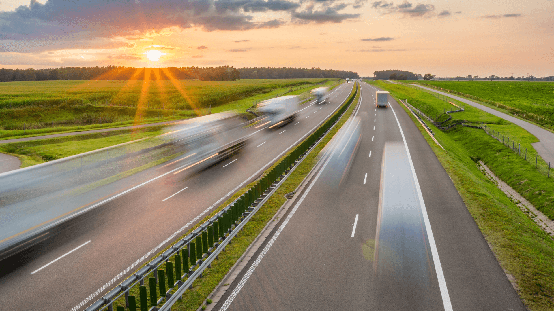 Lorries travelling on a dual carriageway motorway at sunrise, representing UK highways maintenance and transport infrastructure.