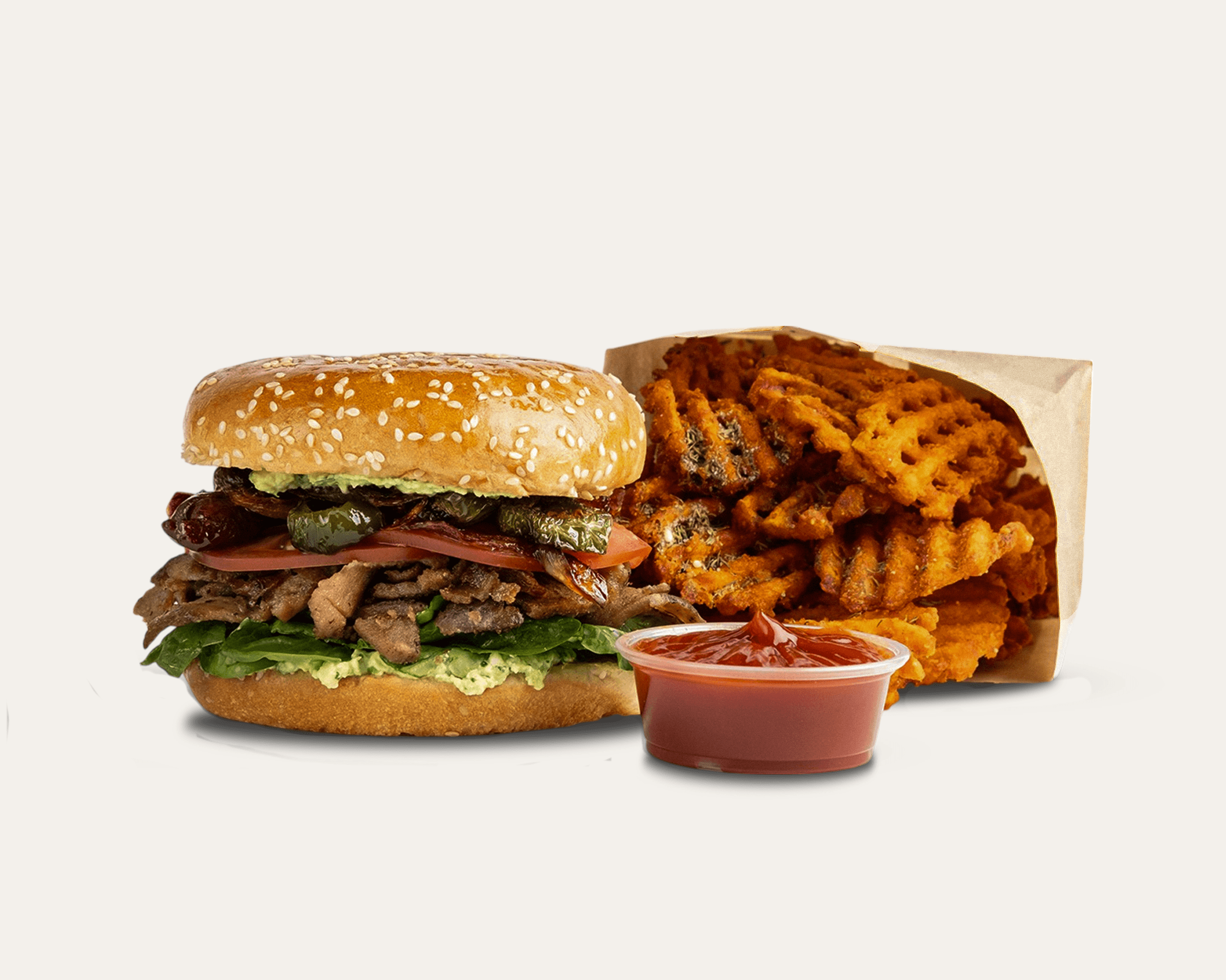 A toasted sandwich layered with Mediterranean meats, tomatoes, pickles, and fresh greens. With a side of waffel cut sweet potato fries and a small container of ketchup