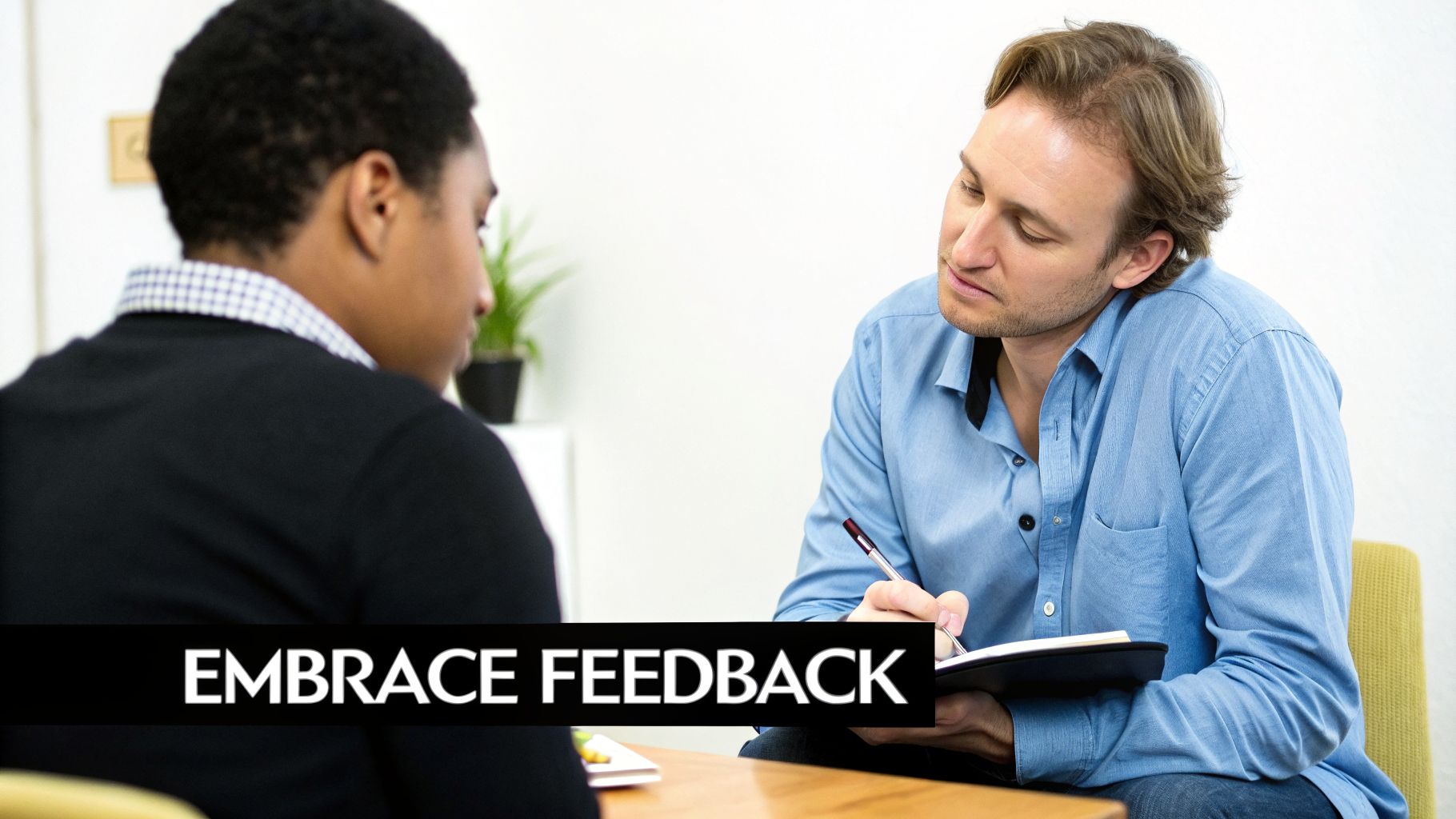 Two men engaged in a feedback or interview session, one writing notes, with 