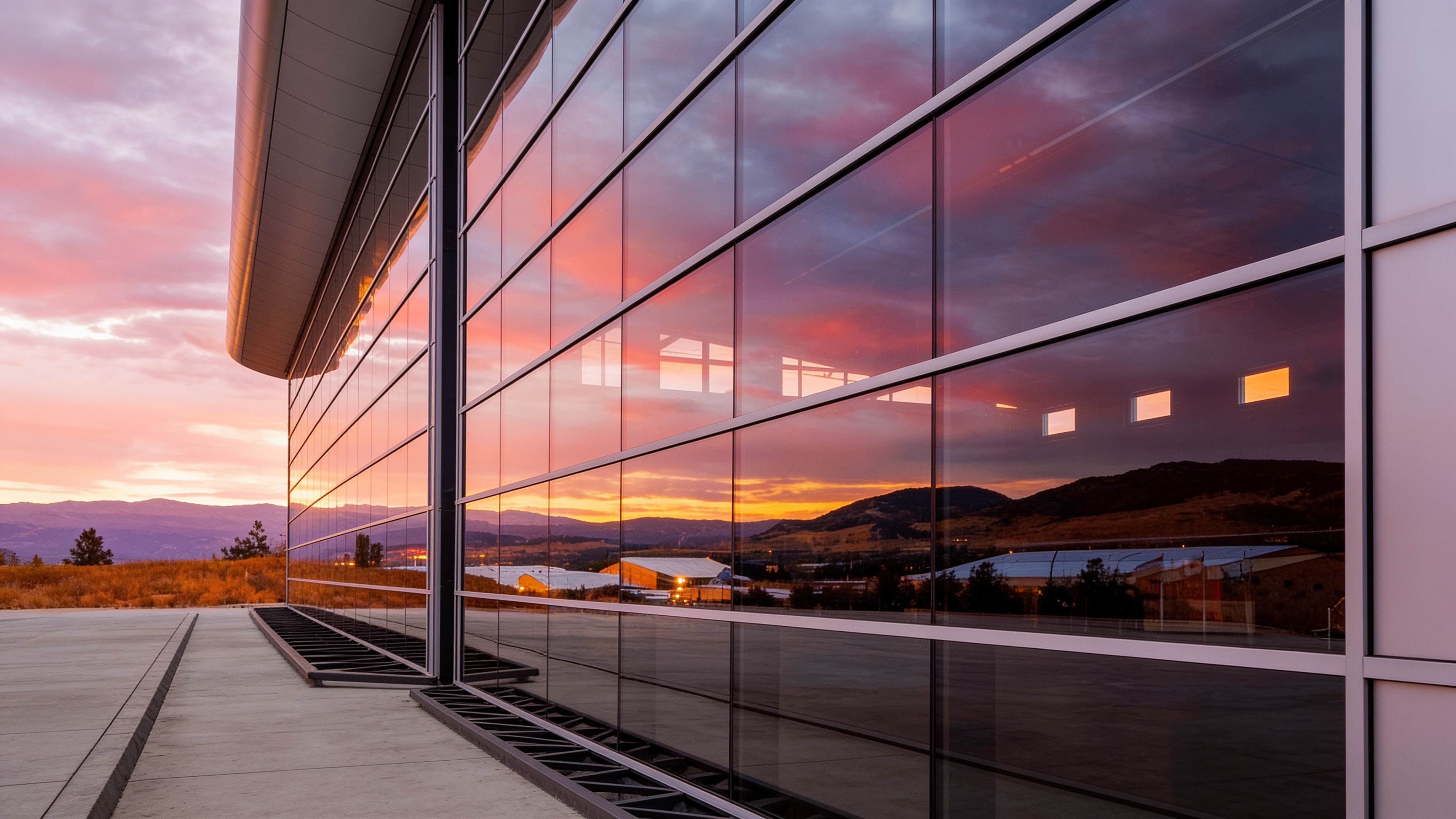 Glass-front building with a PowerLift hydraulic door reflecting a colorful sunset