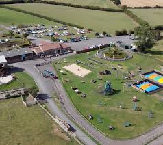 Aerial view of countryside fair with colorful attractions, parking area and festival grounds surrounded by farmland