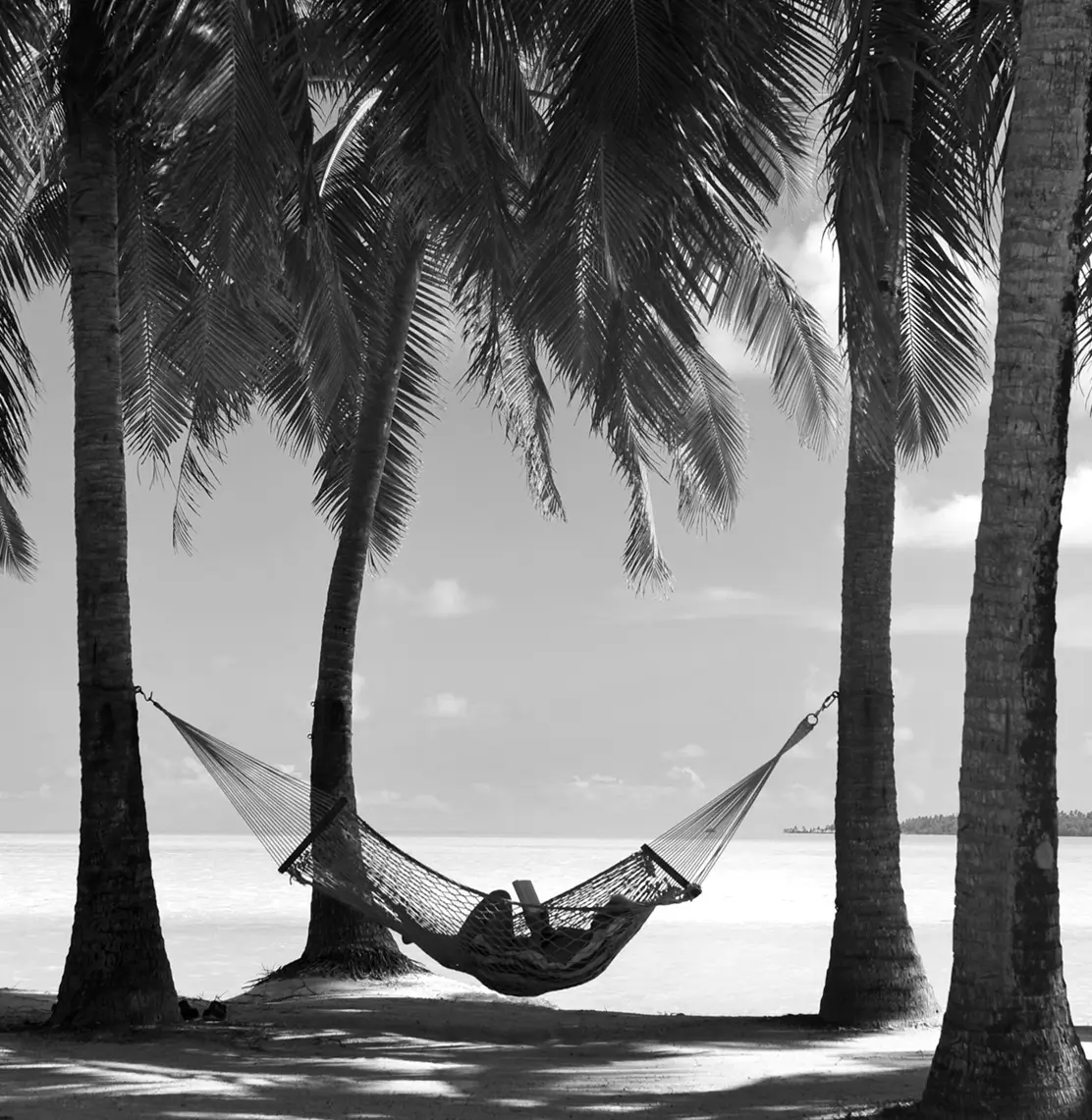 Hammock between palm trees overlooking a turquoise lagoon in the Cook Islands, South Pacific private jet destination
