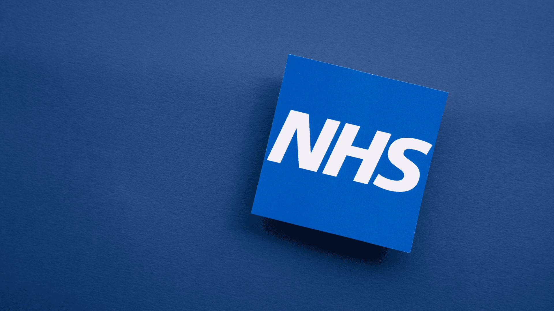 NHS in a blue square on a darker blue background.