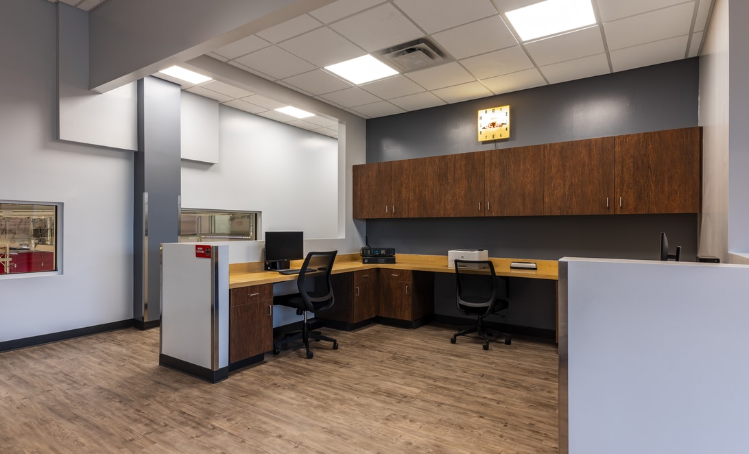 Watch office with dual workstations and wall cabinetry at Midland Fire Station 5, by Martinez Architects.