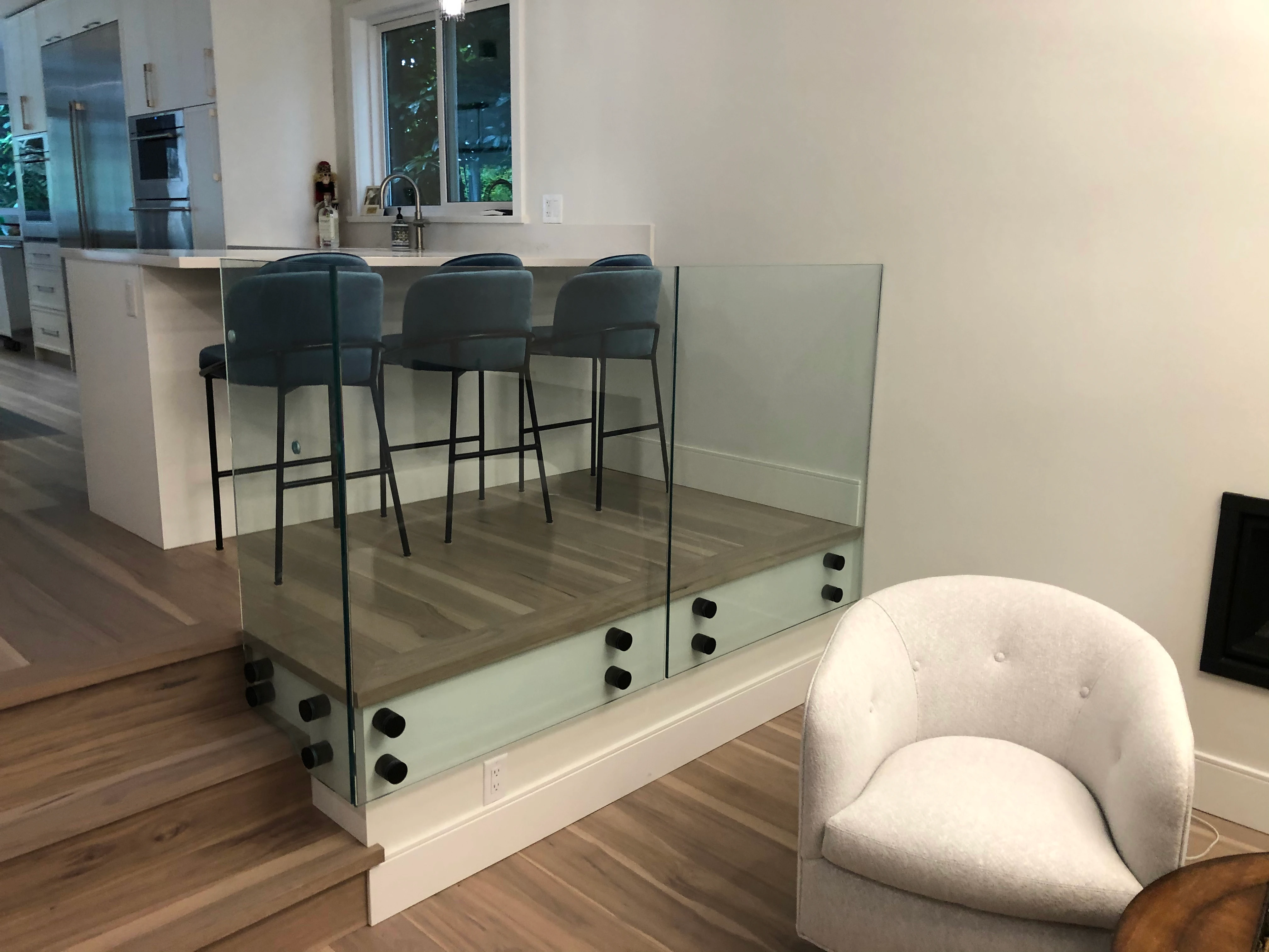 Stainless steel standoff glass railing installed around an upper stair landing