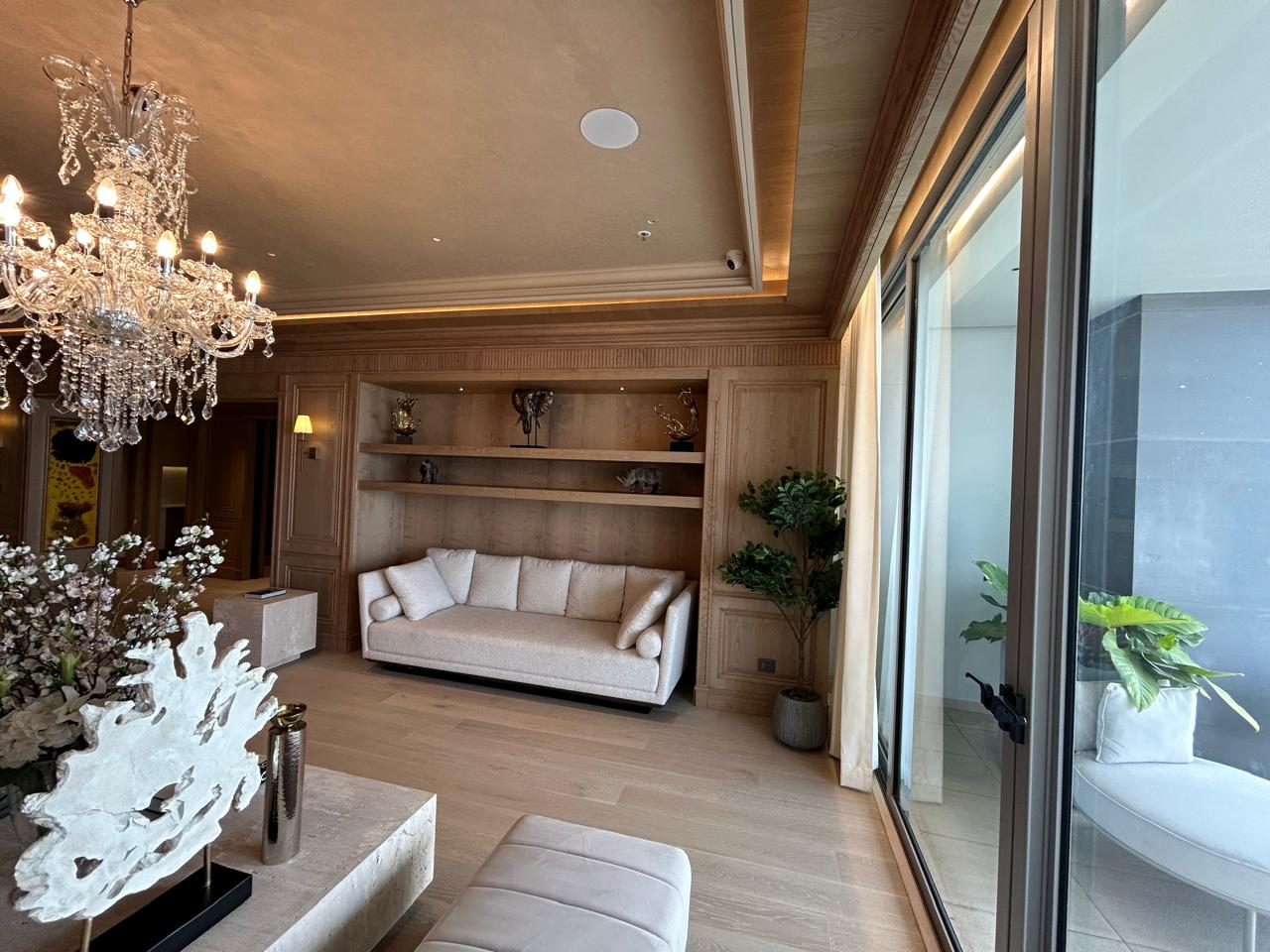 Luxury lounge area with chandelier, classic decor, and bright balcony light.