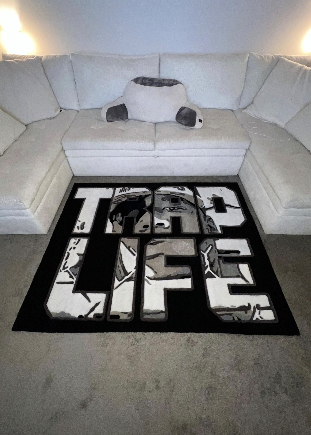Handgetufteter Trap-Life-Teppich vor heller Couch in modernem Wohnraum.
