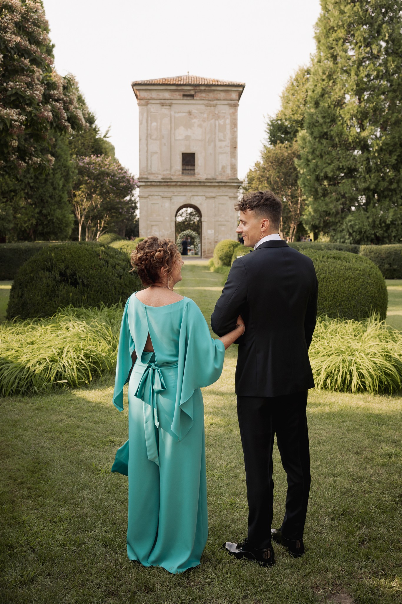 Sposi camminano mano nella mano verso la cappella nel giardino di Villa Negri, reportage di matrimonio in Emilia-Romagna