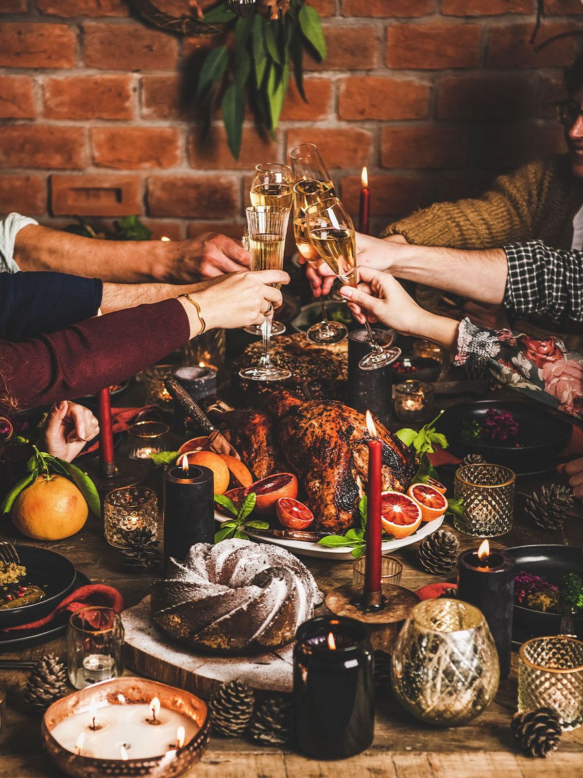 Friends raising champagne glasses over a lavish Christmas feast at Dhoom, surrounded by holiday candles, seasonal fruits, and festive décor creating a warm celebratory atmosphere.
