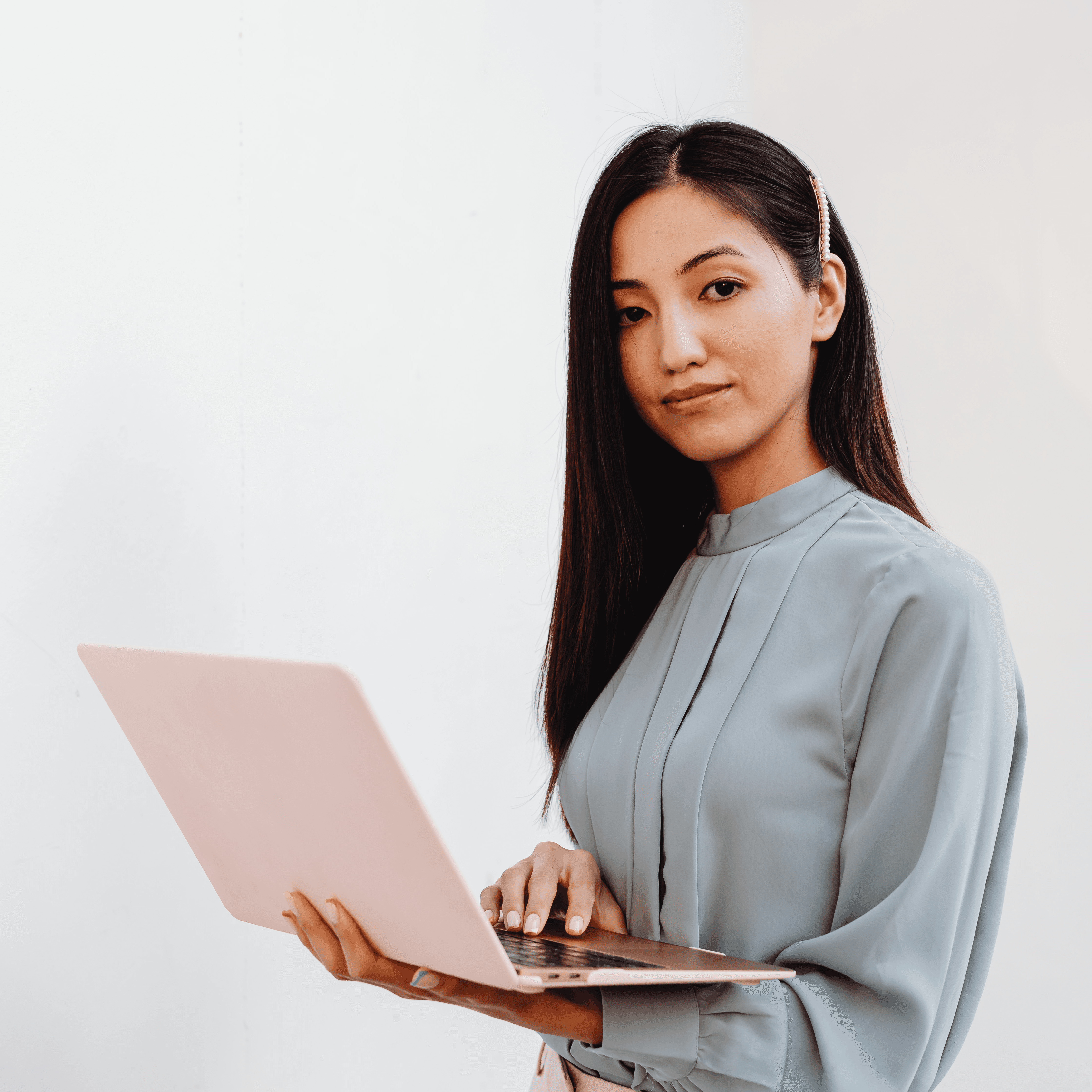 Asian woman holding an open laptop against a white background.