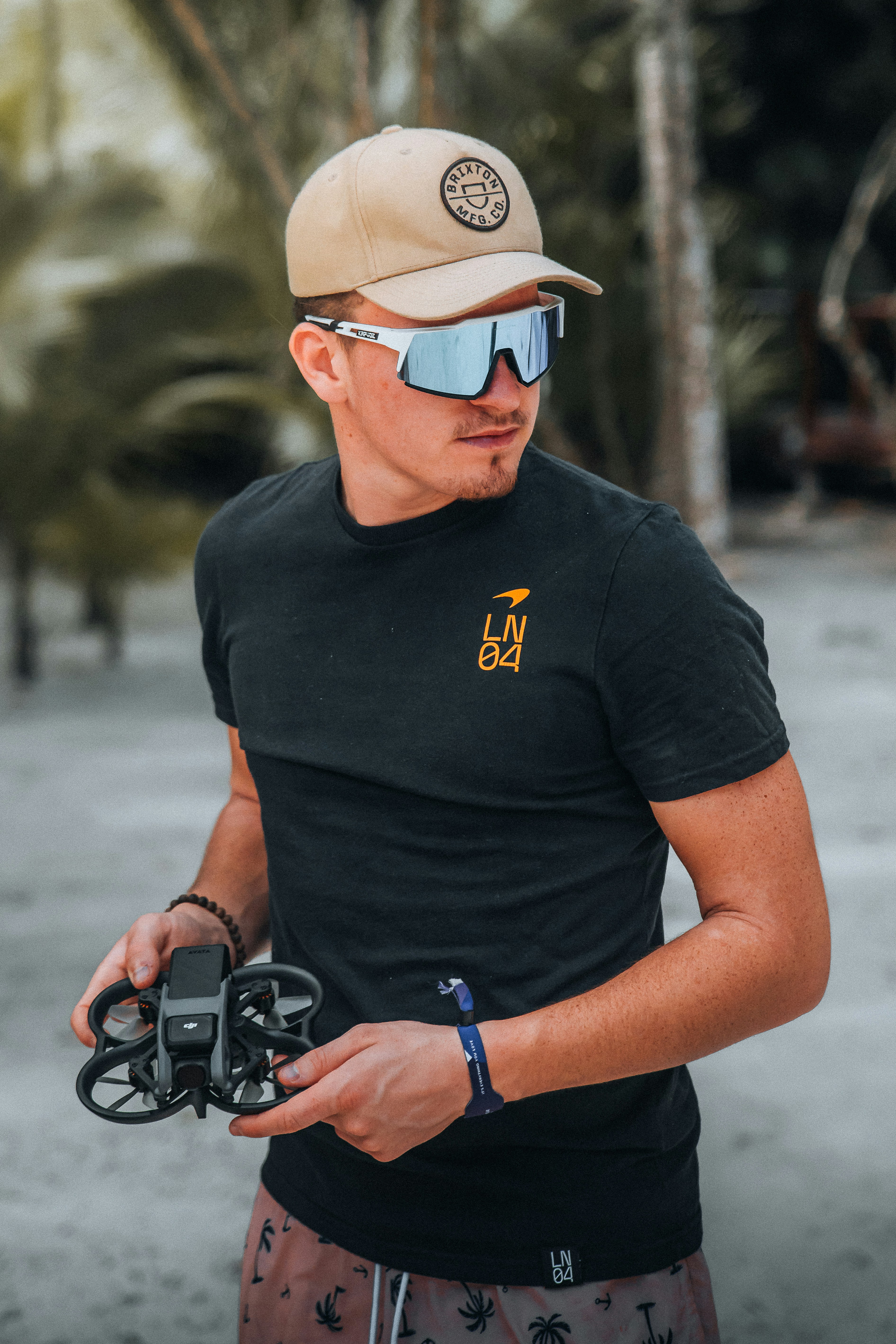 a man wearing a hat and sunglasses holding a small device